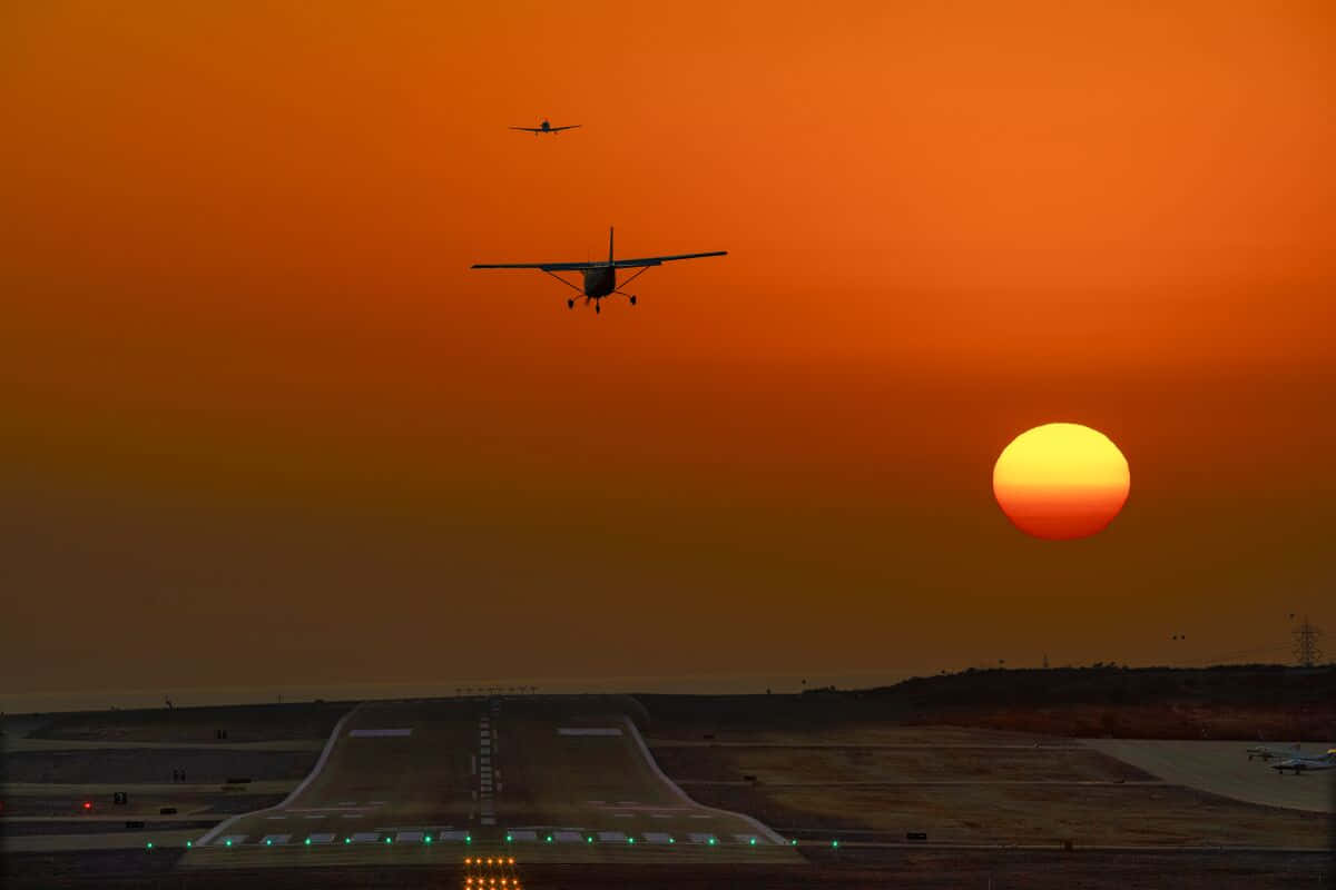 Two Small Airplanes Above Airport Runway Wallpaper