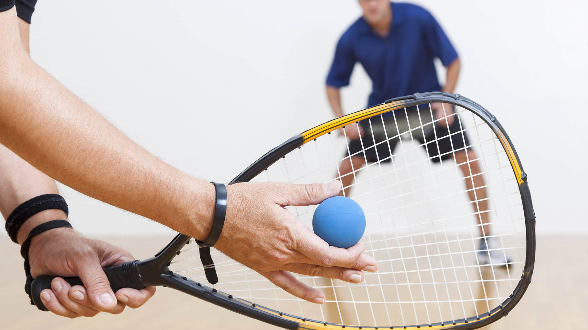 Intense Racquetball Match Between Two Strong Men Wallpaper