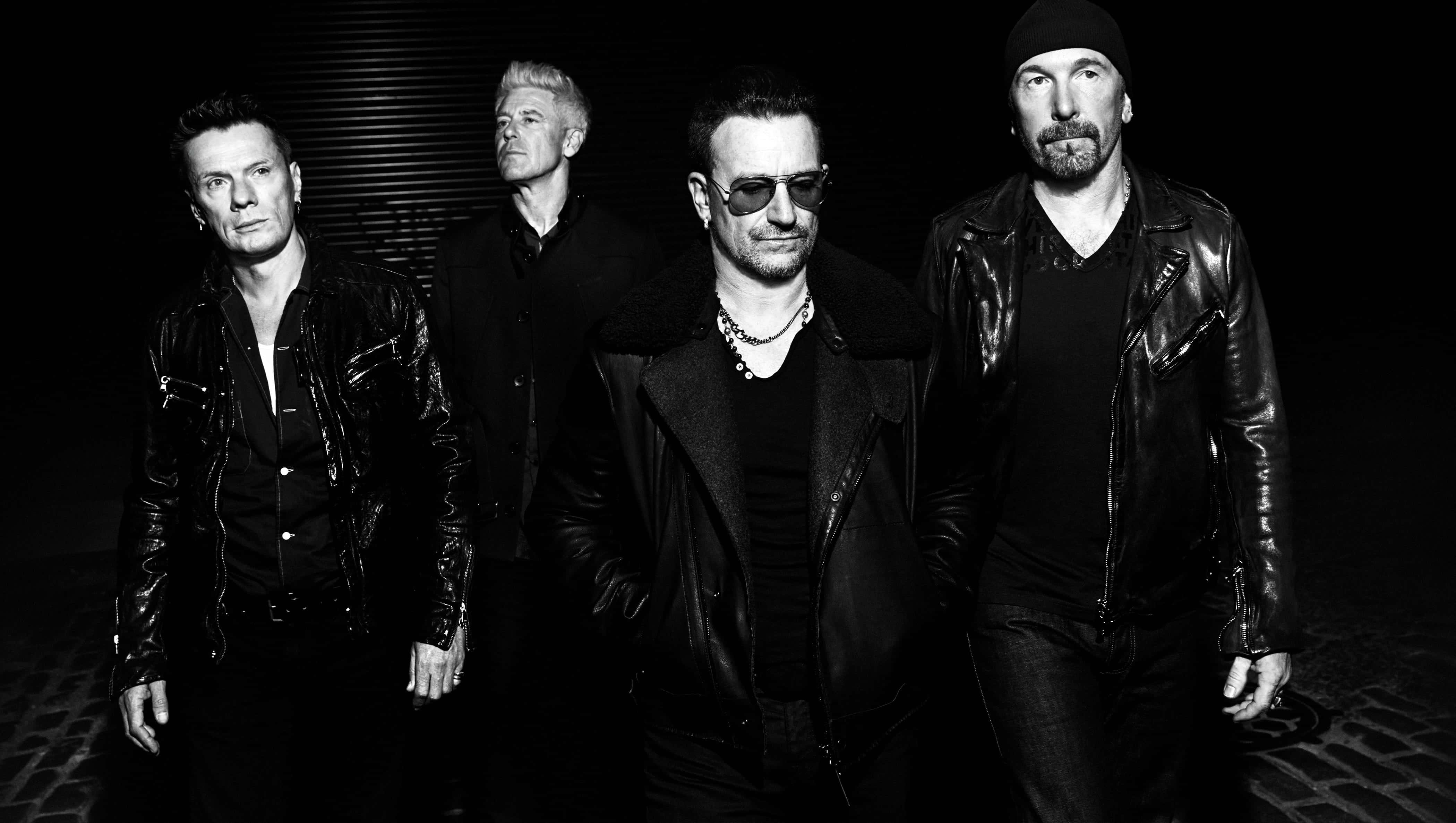 U2 Band Performing In A Concert Under Vibrant Lights Wallpaper