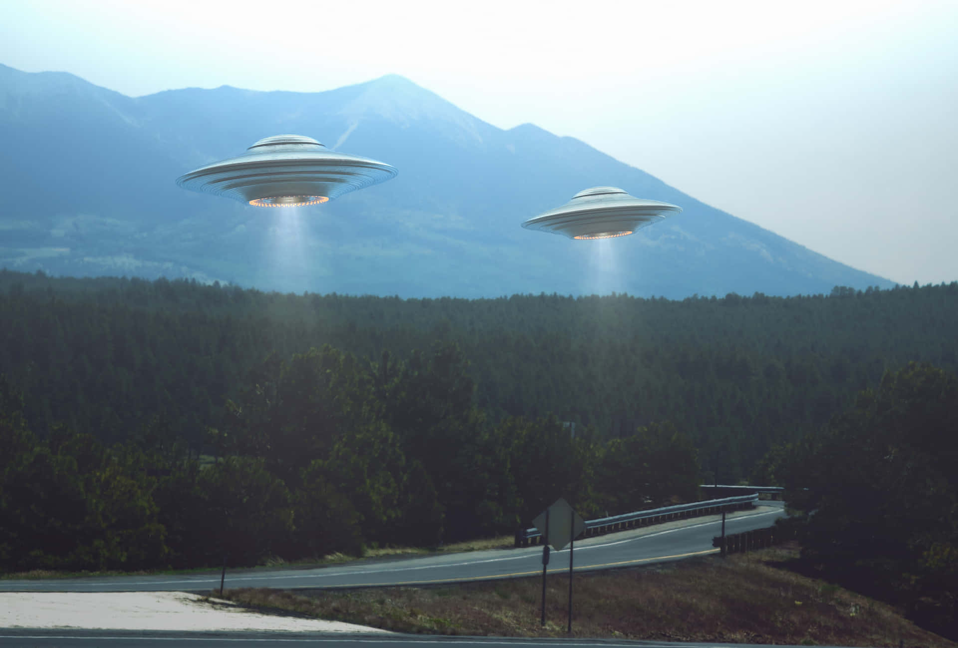 Two Ufos Flying Over A Road In The Mountains