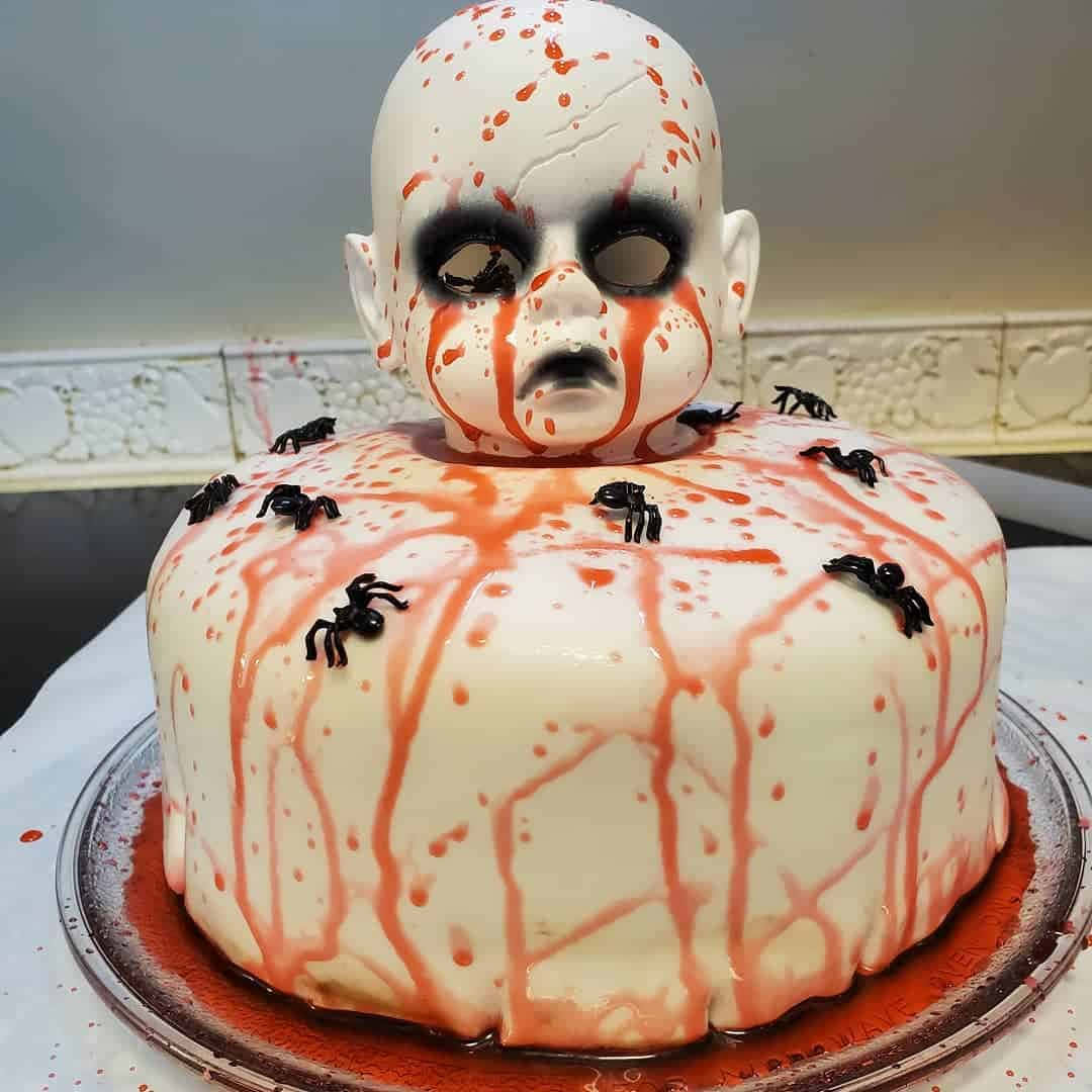 A Cake With A Head Covered In Blood And Spiders