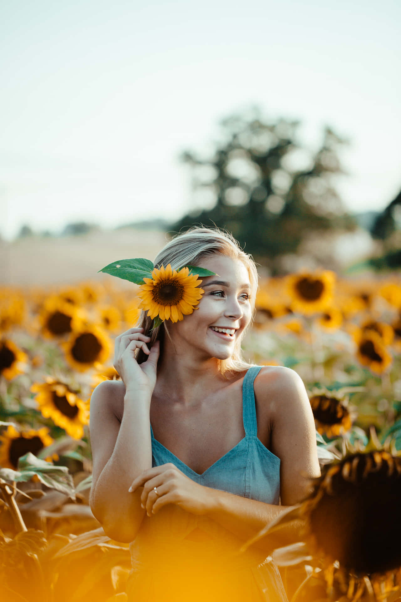 Einefrau Lächelt In Einem Sonnenblumenfeld.