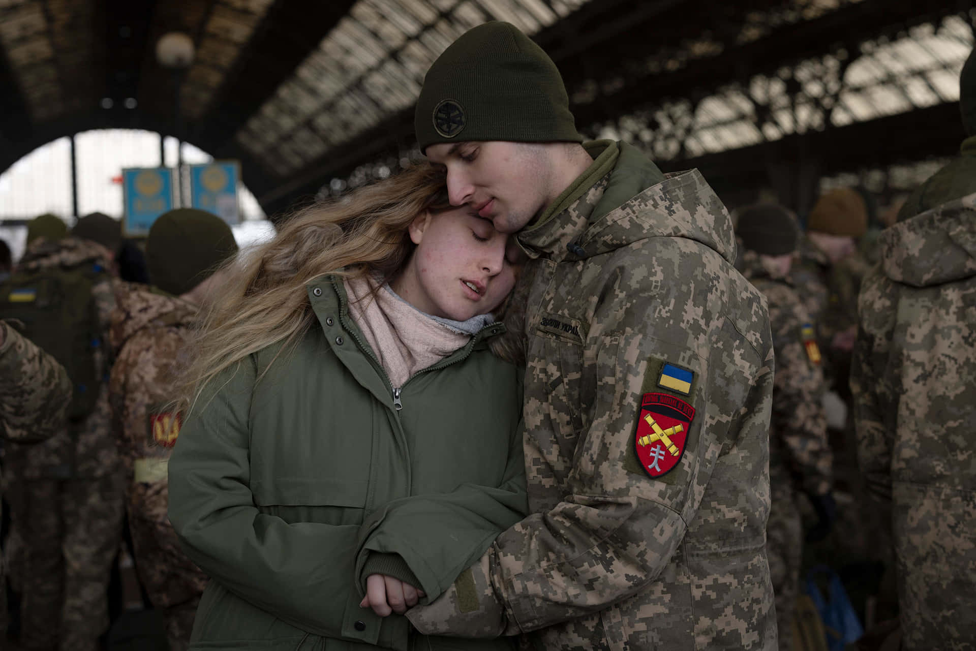 A Woman And A Man Hugging In A Military Station