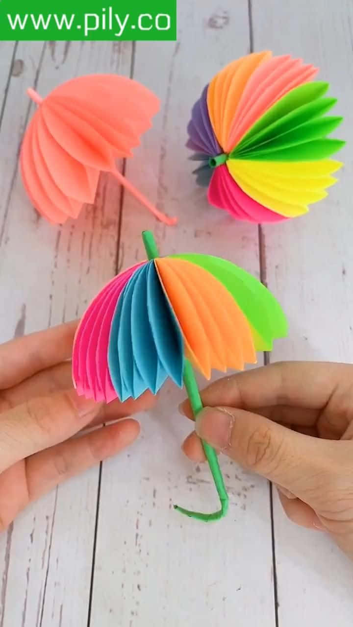 A Person Is Holding Up A Colorful Paper Umbrella