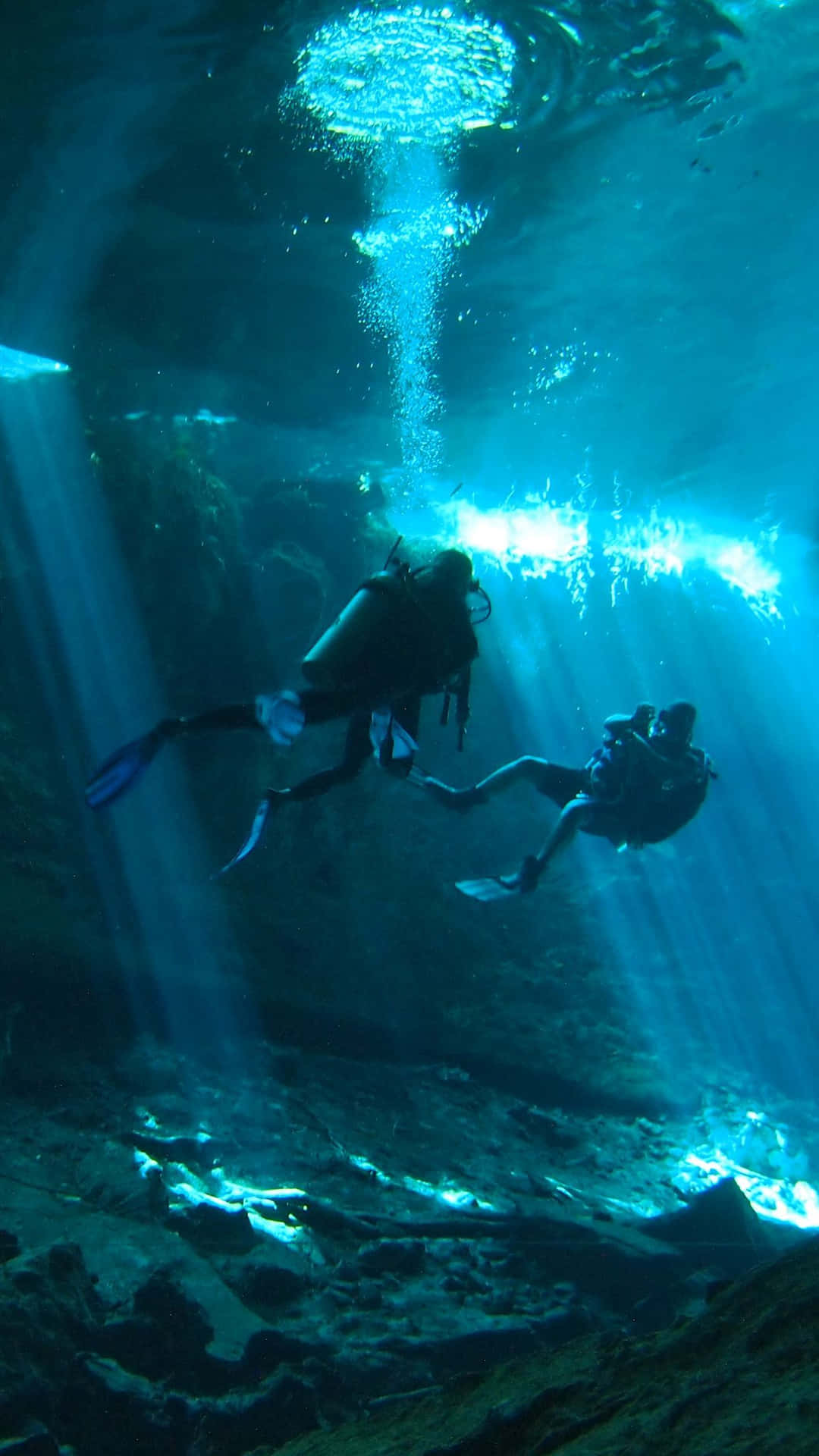 dykning med scuba i en hule med sollys der skinner igennem Wallpaper