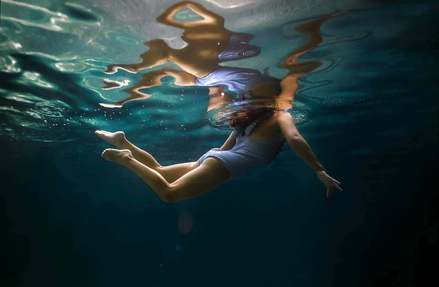 Enkvinde Svømmer Under Vandet Med Strakte Ben.
