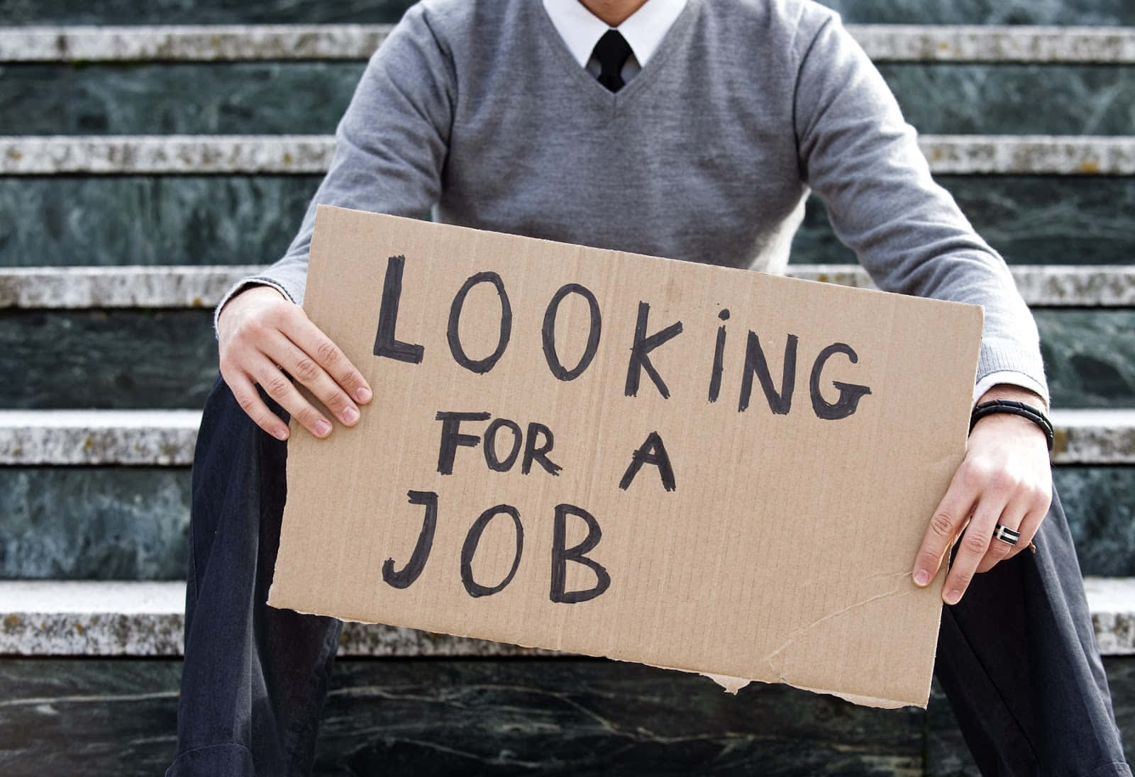 Desperate job seeker holding a "Need a job" sign