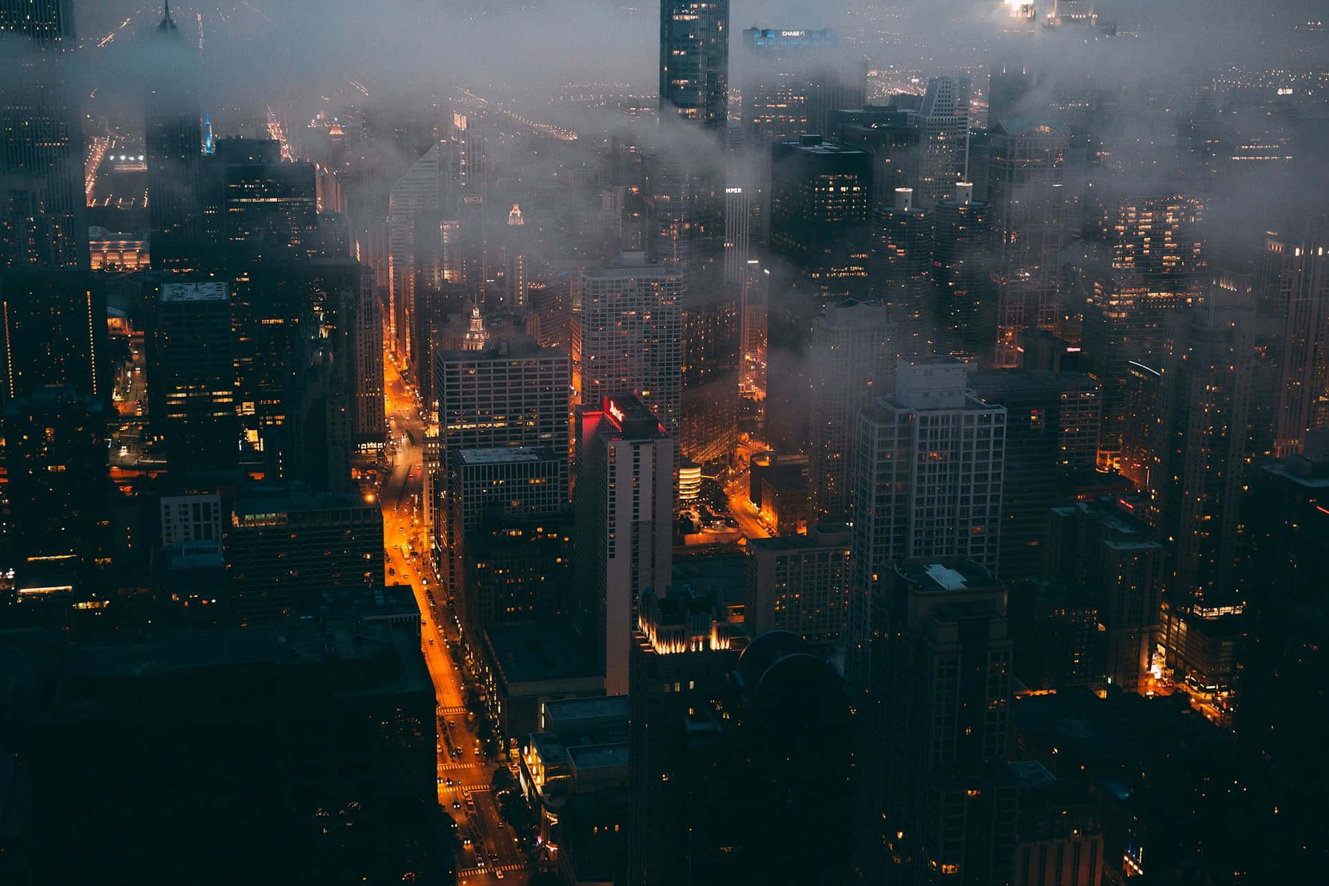 A Cityscape With Buildings And Fog At Night