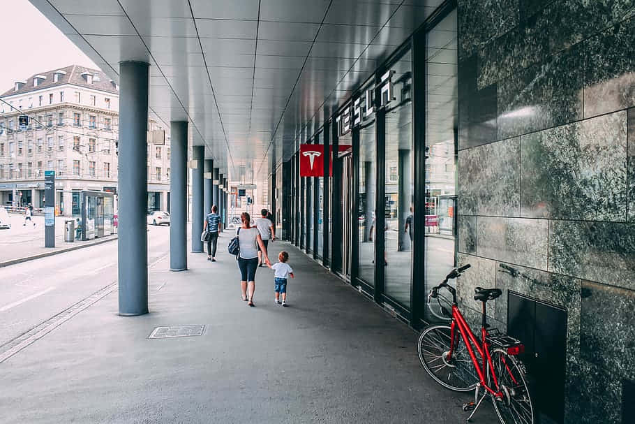 Urban Walkway Tesla Storefront Family Stroll Wallpaper