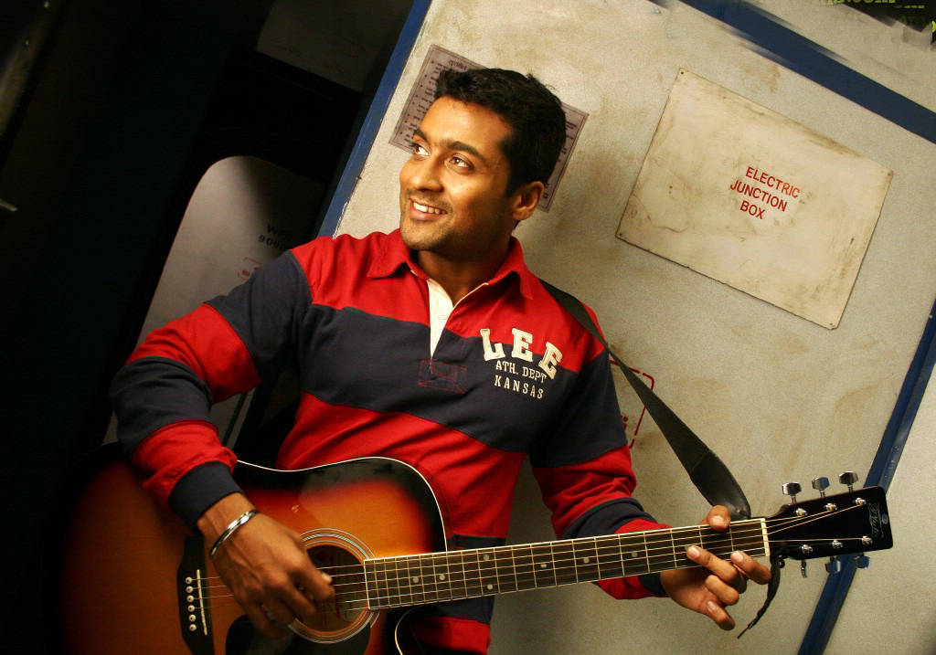 Vaaranam Aayiram Surya Smilende Mens Du Spiller En Guitar Wallpaper