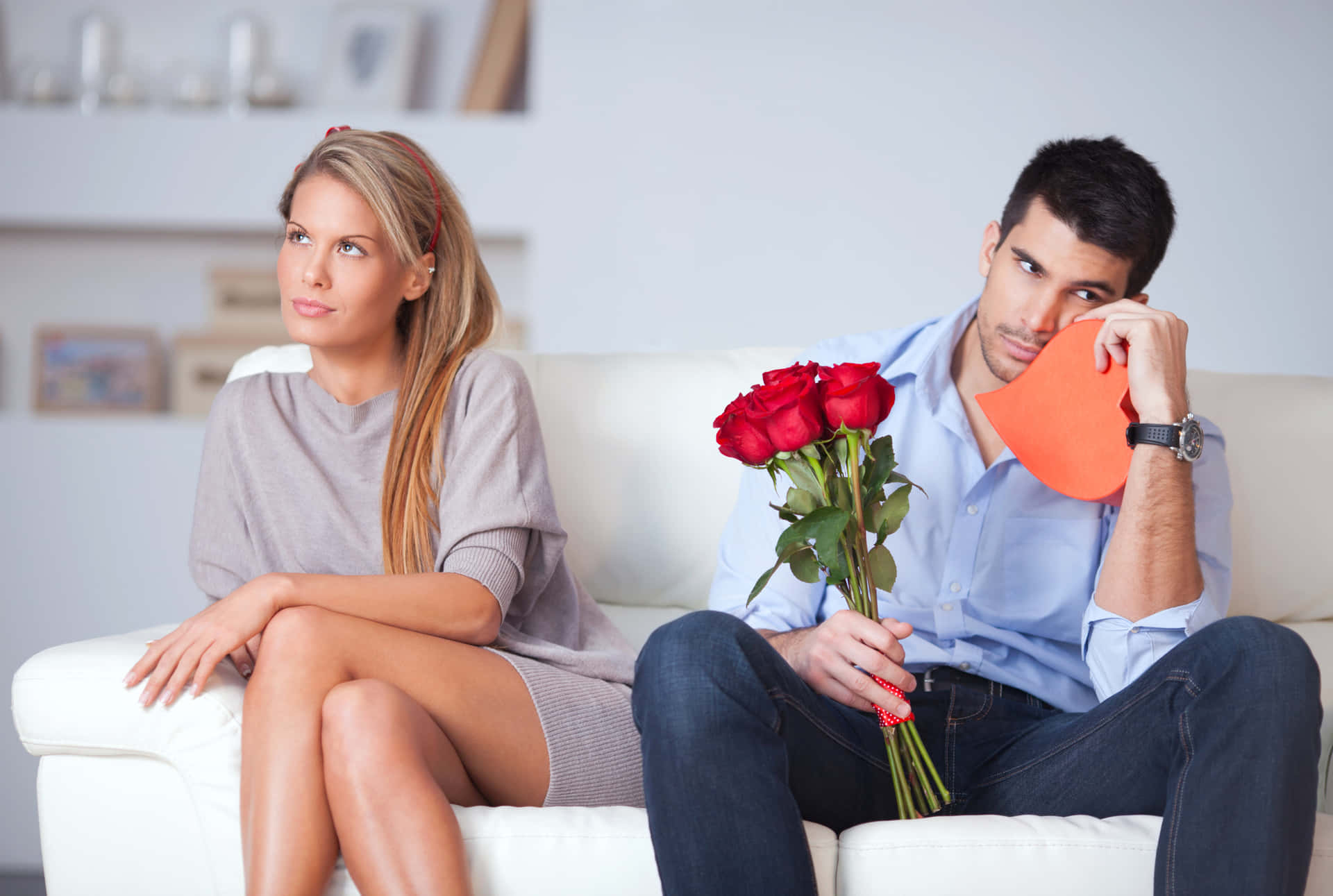 A Man And Woman Sitting On A Couch Holding Roses