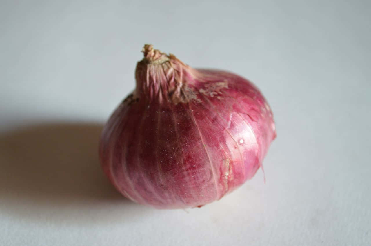 A Red Onion On A White Surface