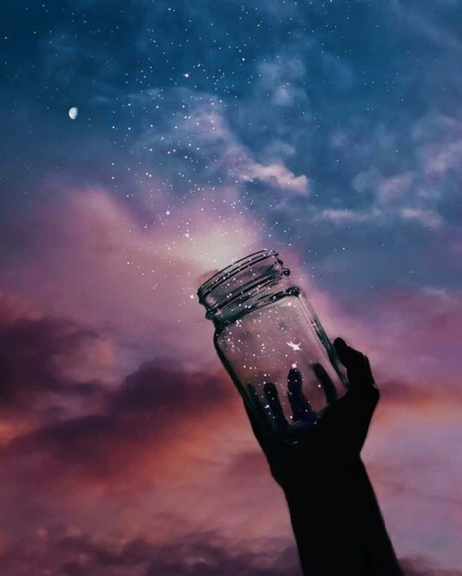 A Hand Holding A Jar With Stars In The Sky