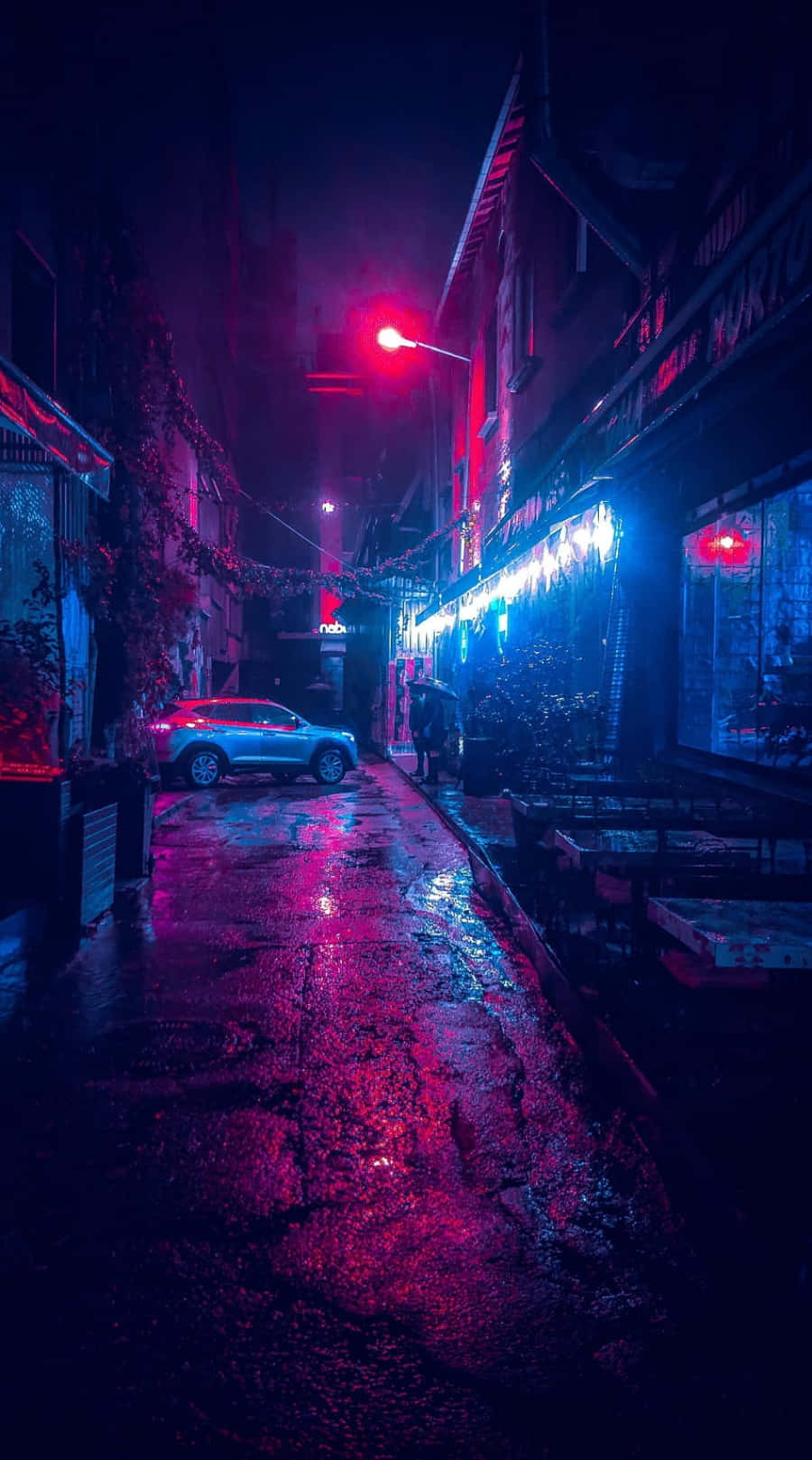 A Street With Neon Lights And Cars At Night