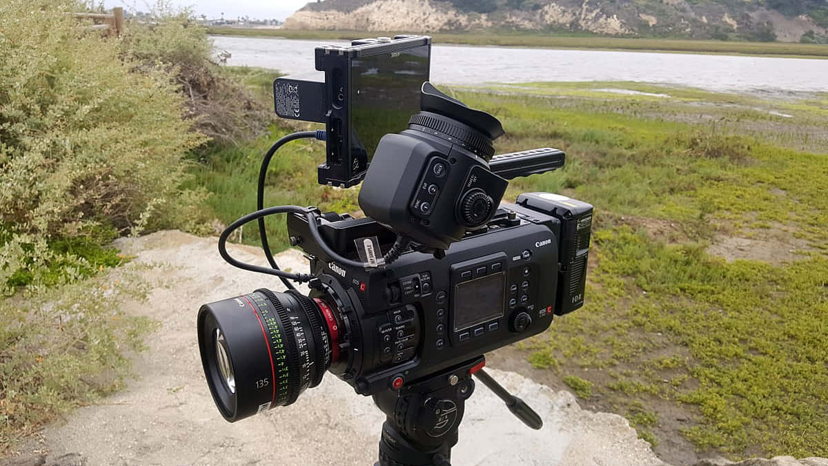 A Camera Is Sitting On A Tripod Near A Body Of Water Wallpaper