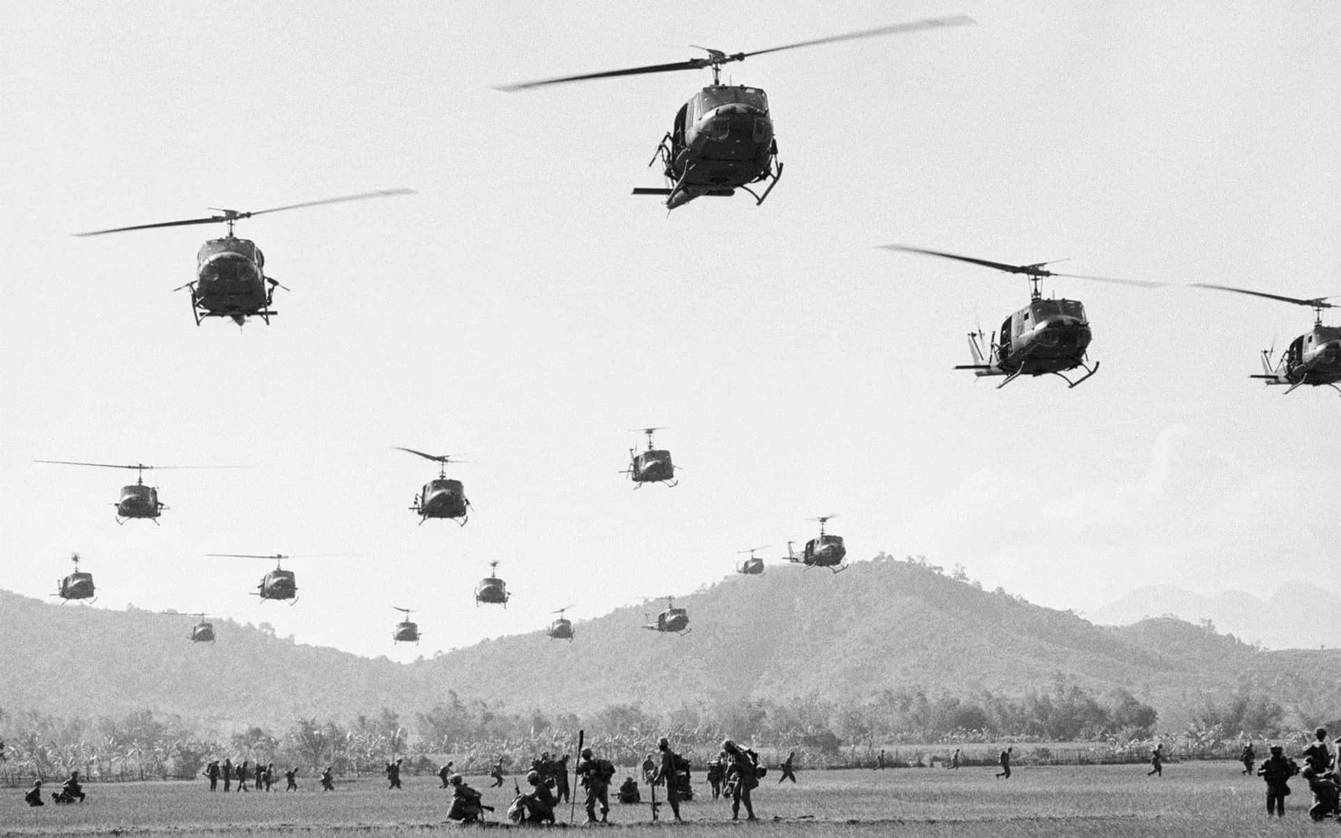 A Group Of Helicopters Flying Over A Field