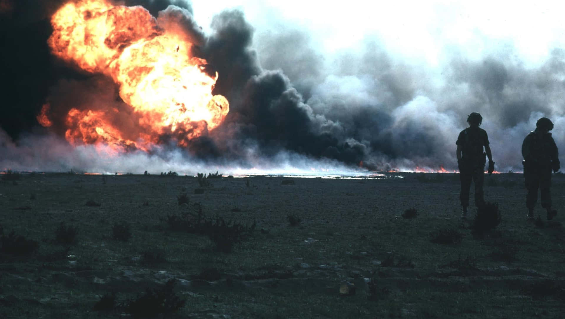 Two Men Standing In Front Of A Large Fire