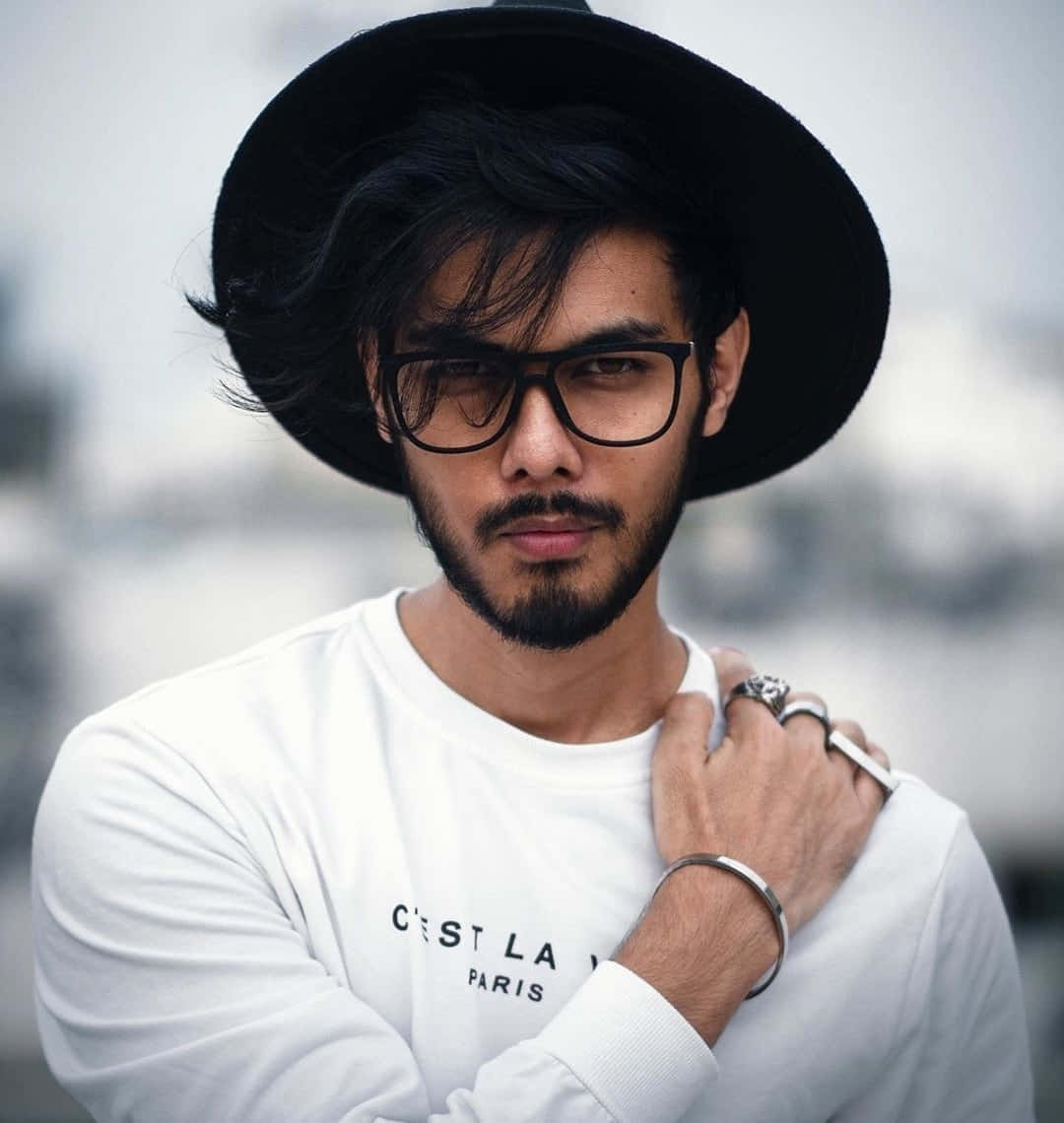 A Man In A Hat And Glasses Posing For A Photo