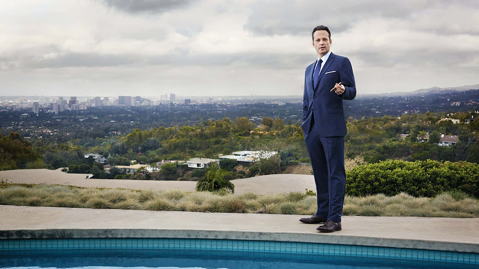 Vince Vaughn posing in a stylish outfit against a captivating backdrop Wallpaper