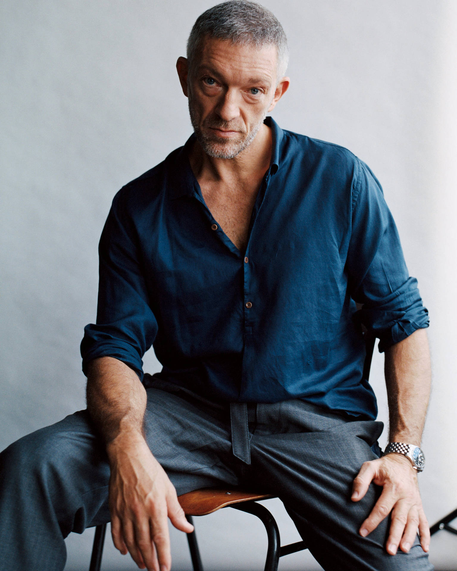 Renowned Actor Vincent Cassel Contemplatively Sitting on a Chair Wallpaper