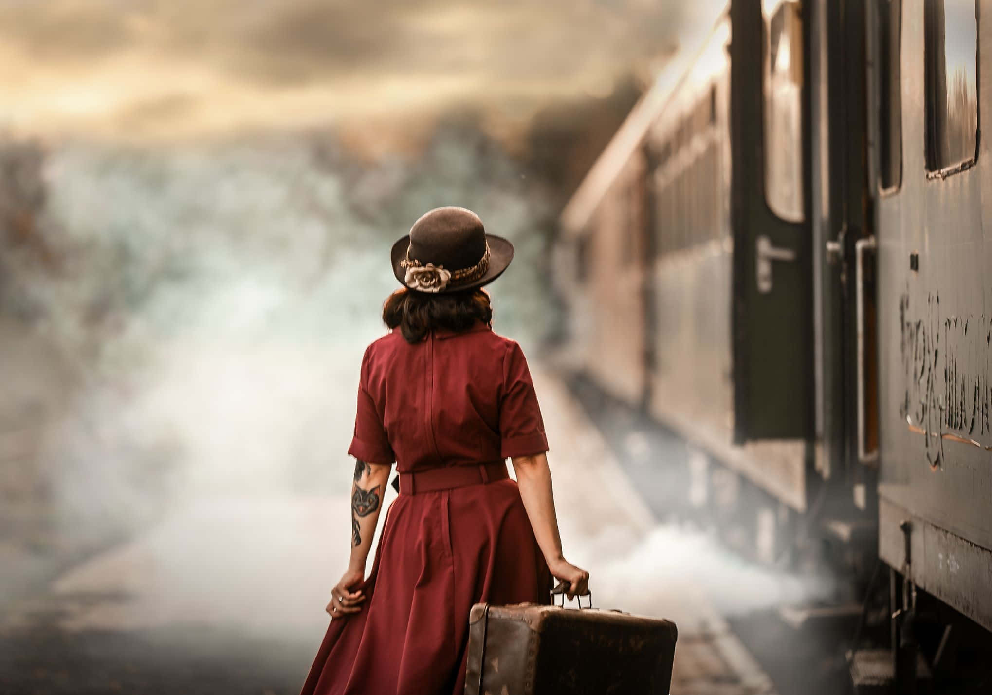 A Woman In A Red Dress Is Standing Next To A Train