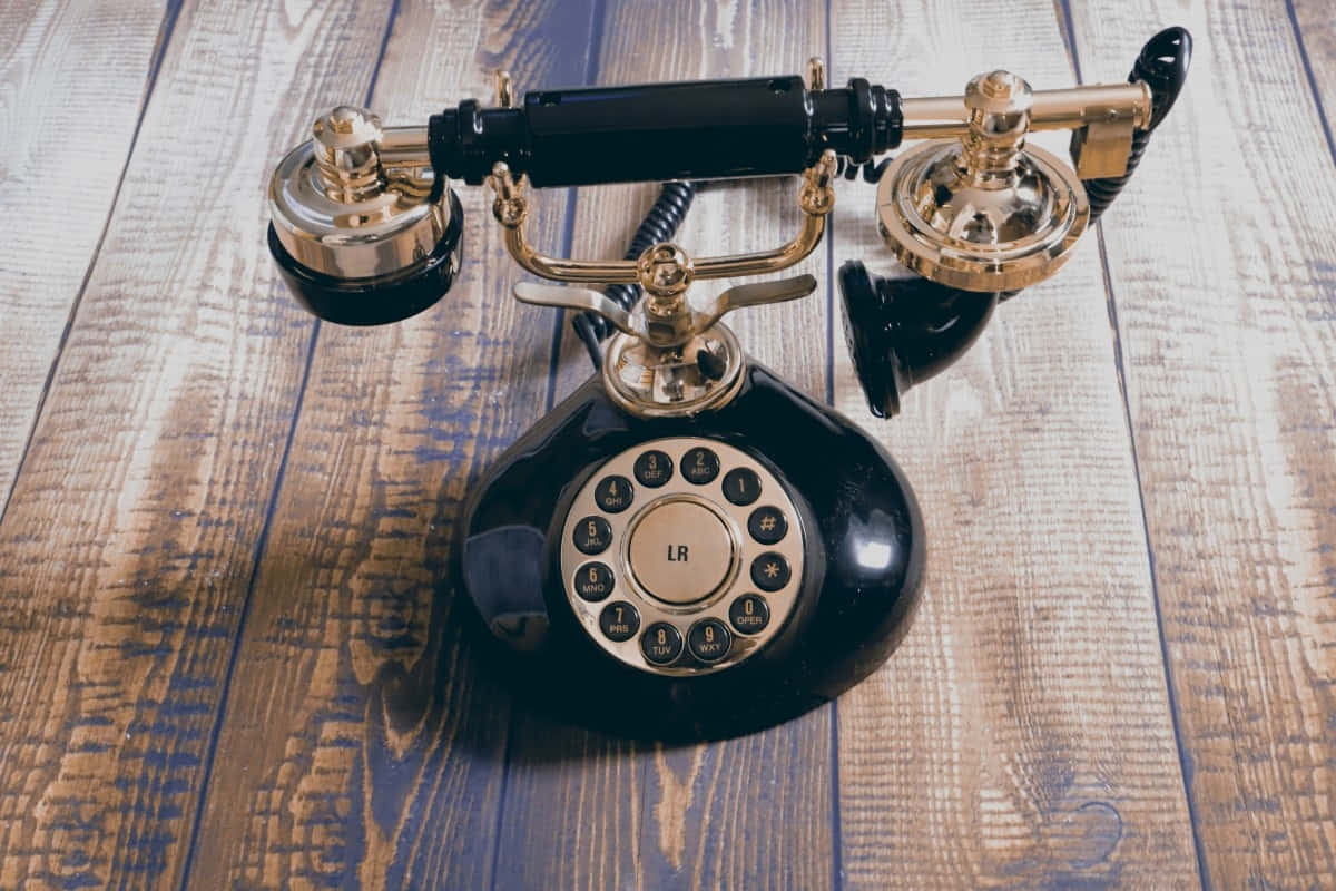 Vintage Black Rotary Telephoneon Wooden Table Wallpaper