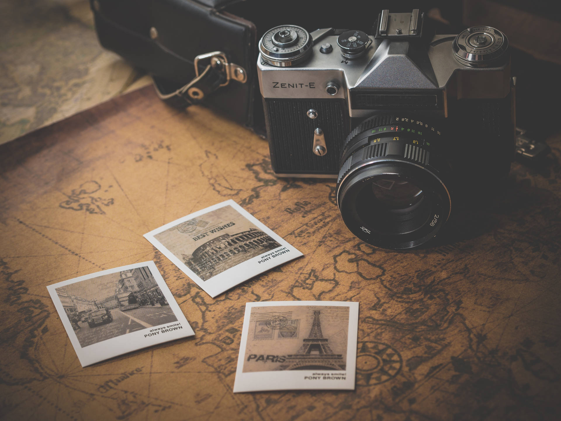 Vintage camera and retro style photos on a brown map wallpaper