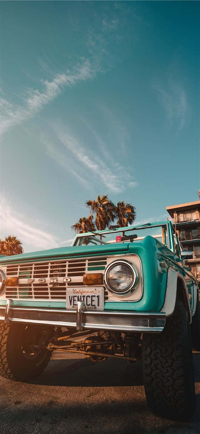 A Turquoise Truck Parked In Front Of A Palm Tree Wallpaper
