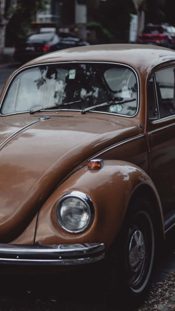 Et gammelt tan Volkswagen Beetle parkeret på siden af vejen. Wallpaper