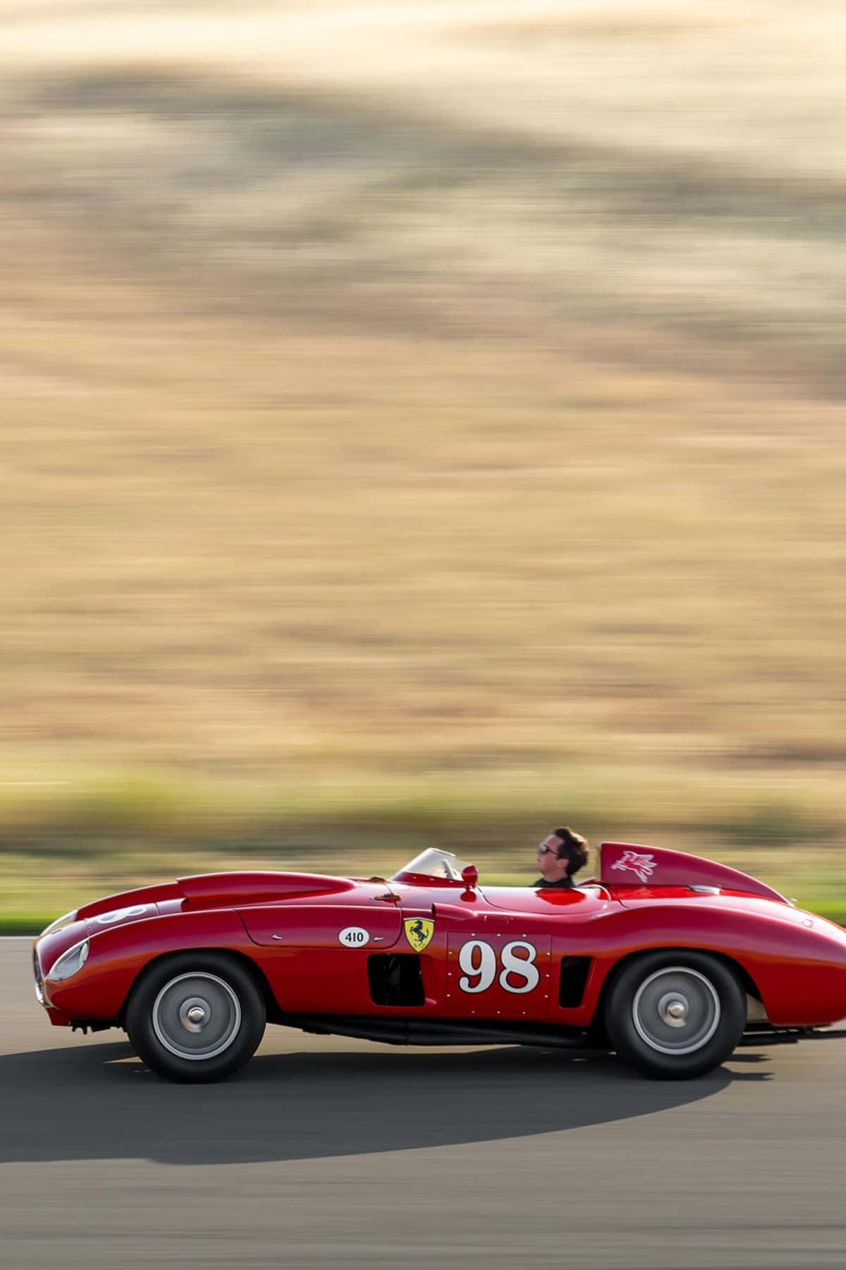 A Man Driving A Red Racing Car On A Track Wallpaper