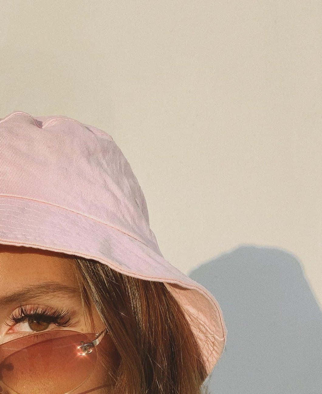 A Woman Wearing A Pink Bucket Hat And Sunglasses Wallpaper