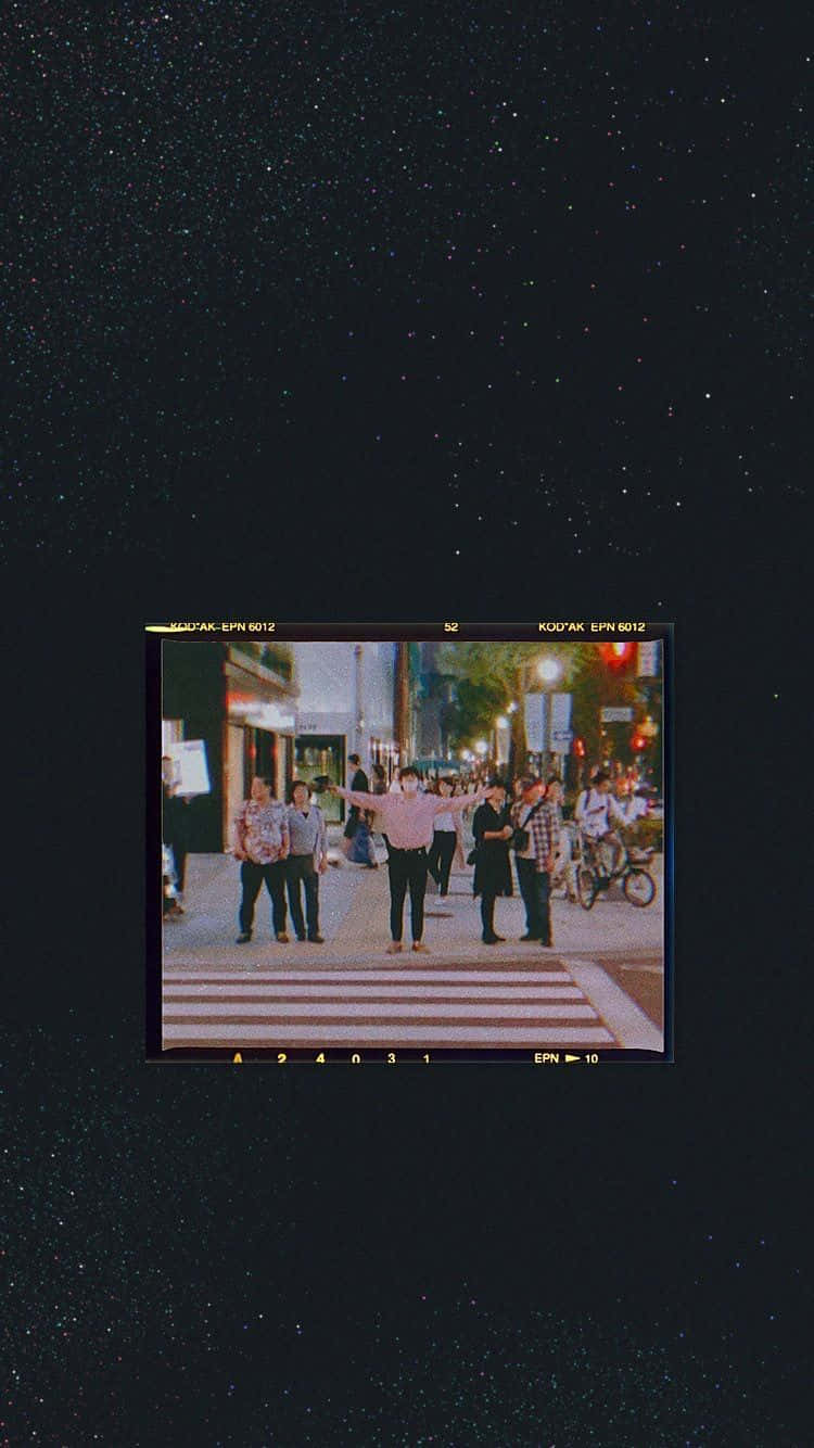 Et sort skærme med et billede af mennesker på en gade. Wallpaper