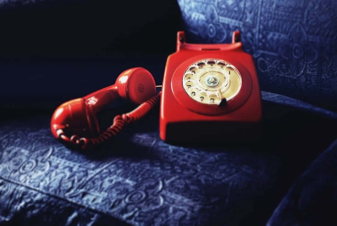 Vintage Red Rotary Phoneon Couch Wallpaper