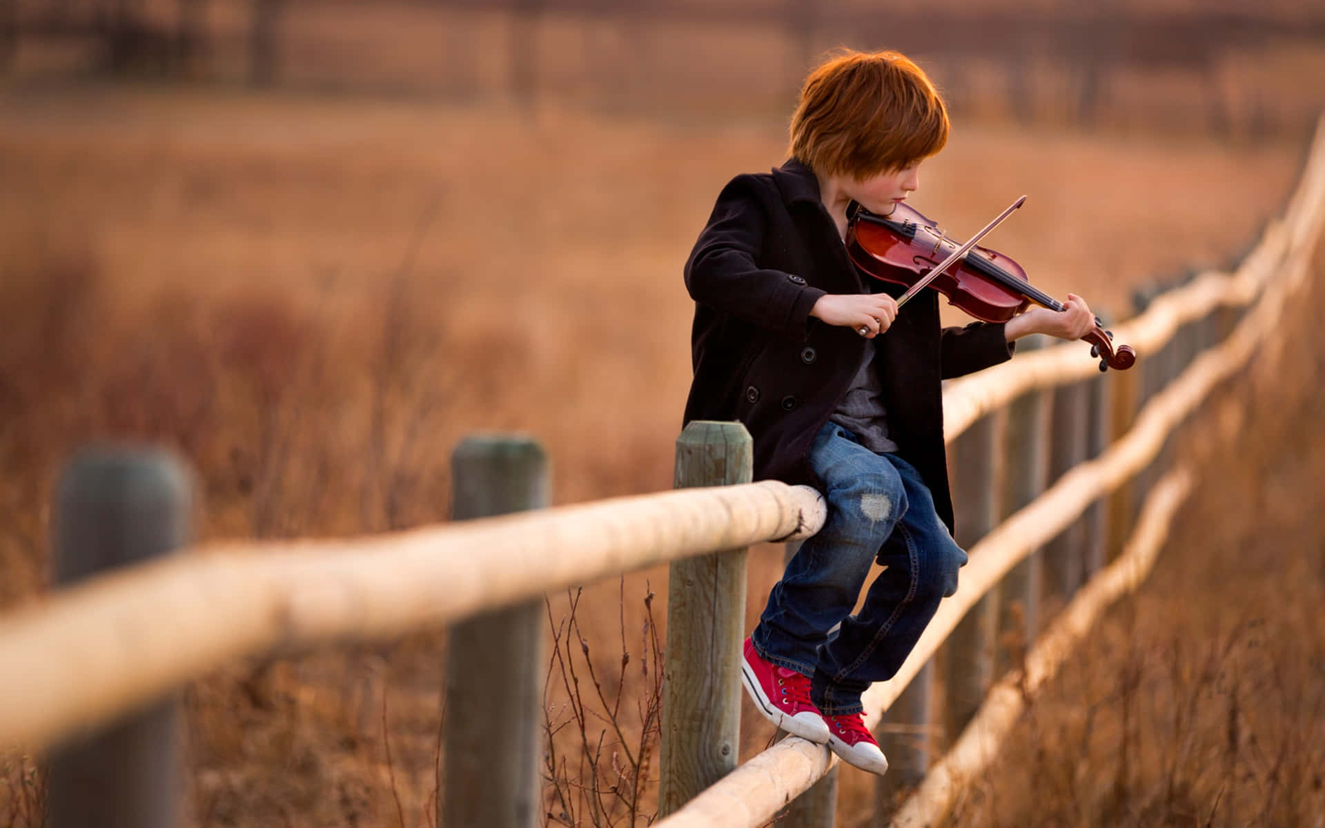 Pojkesom Spelar Violin På Staketbild.