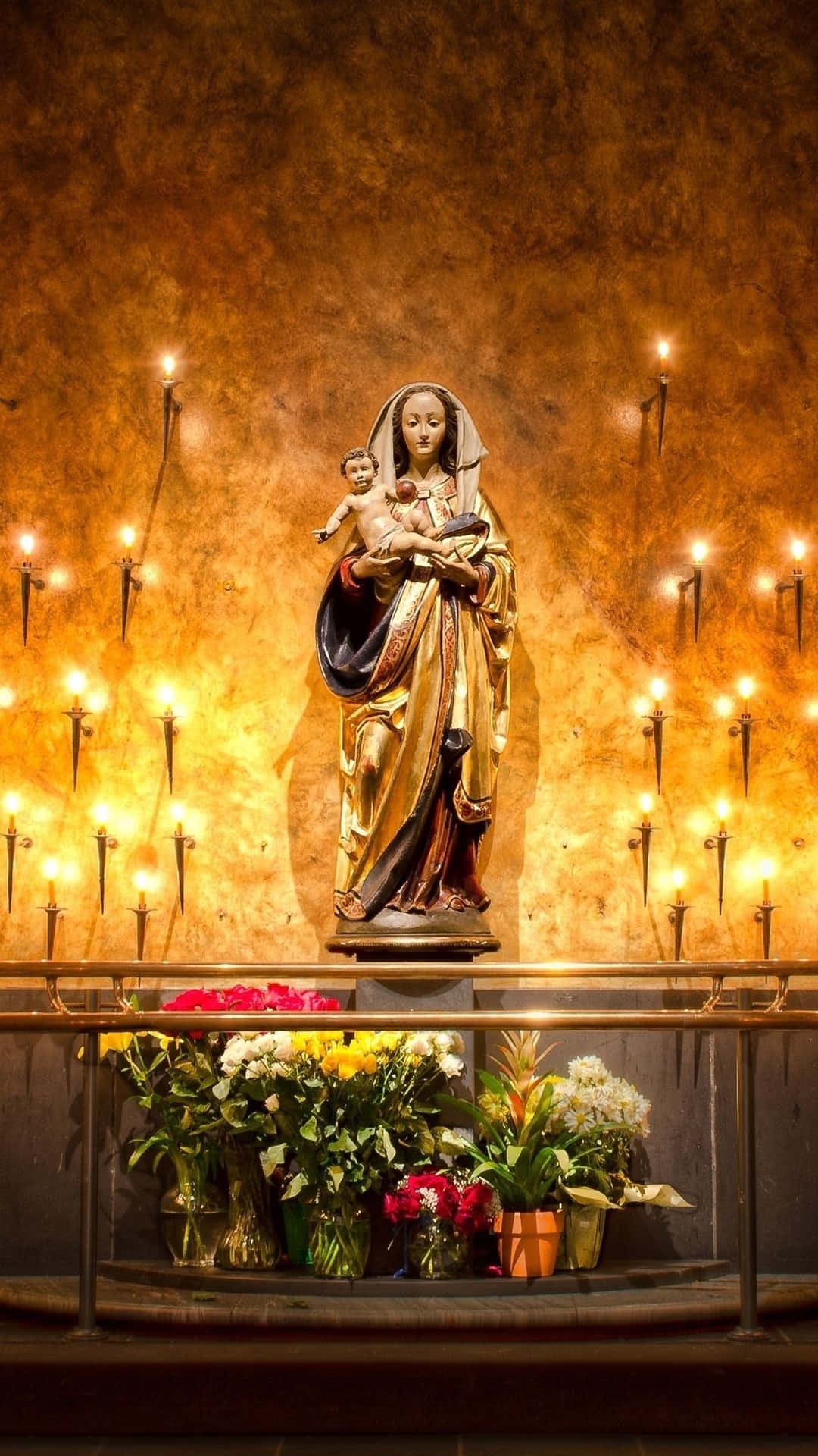 Virgin Mary Statuewith Candlesand Flowers Wallpaper