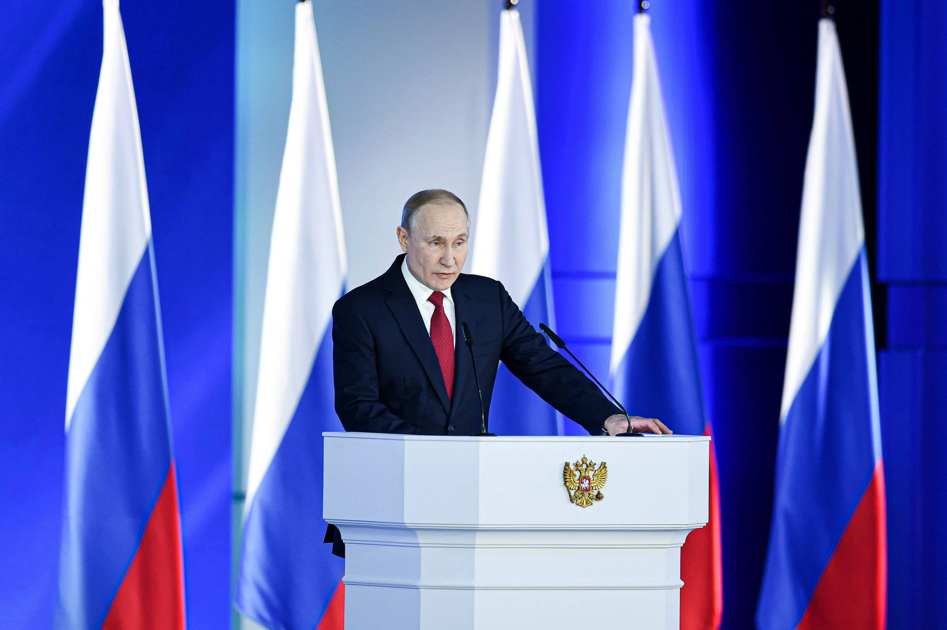 Vladimir Putin With Five Flags Behind Picture