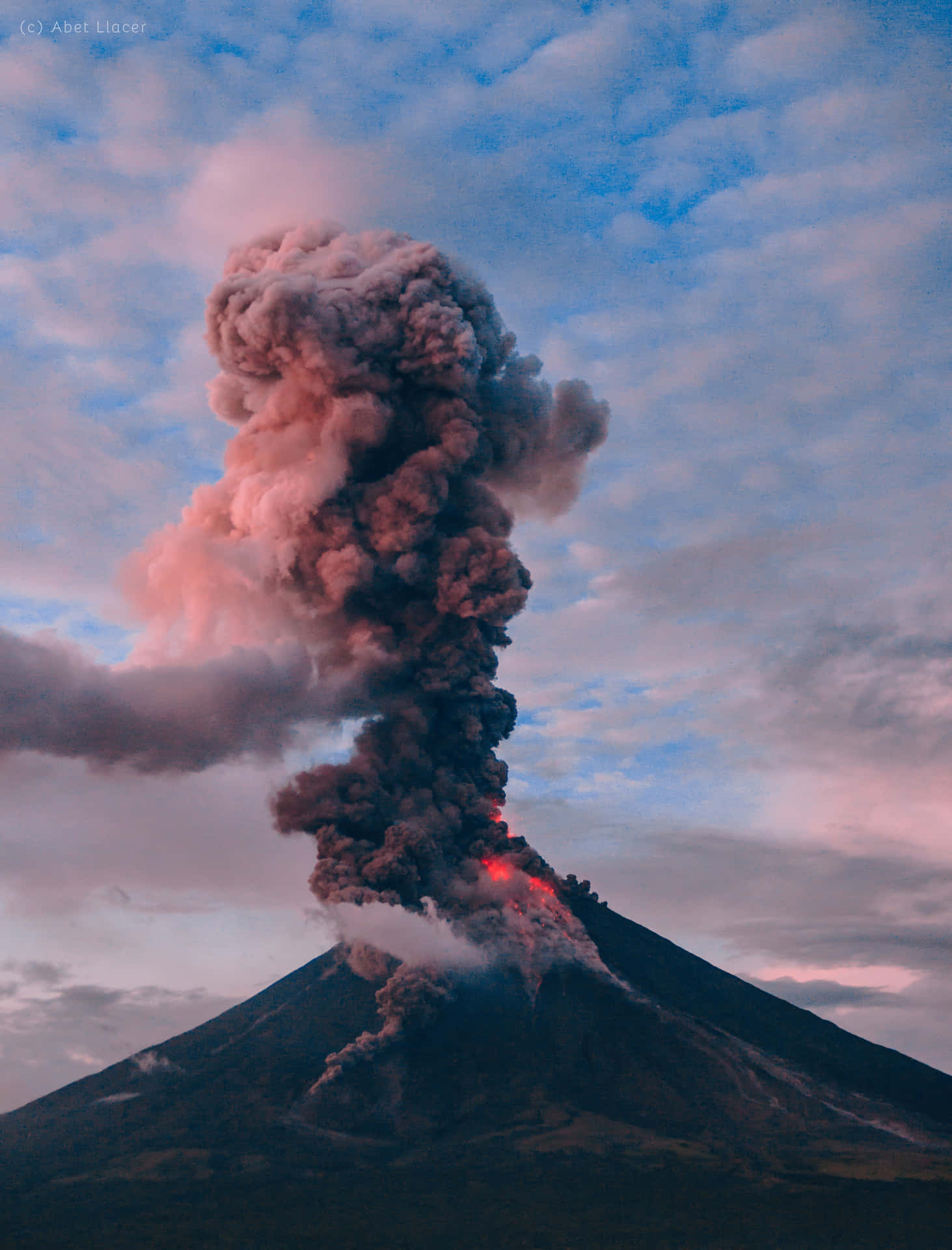 A blazing orange sunrise over a steaming volcano