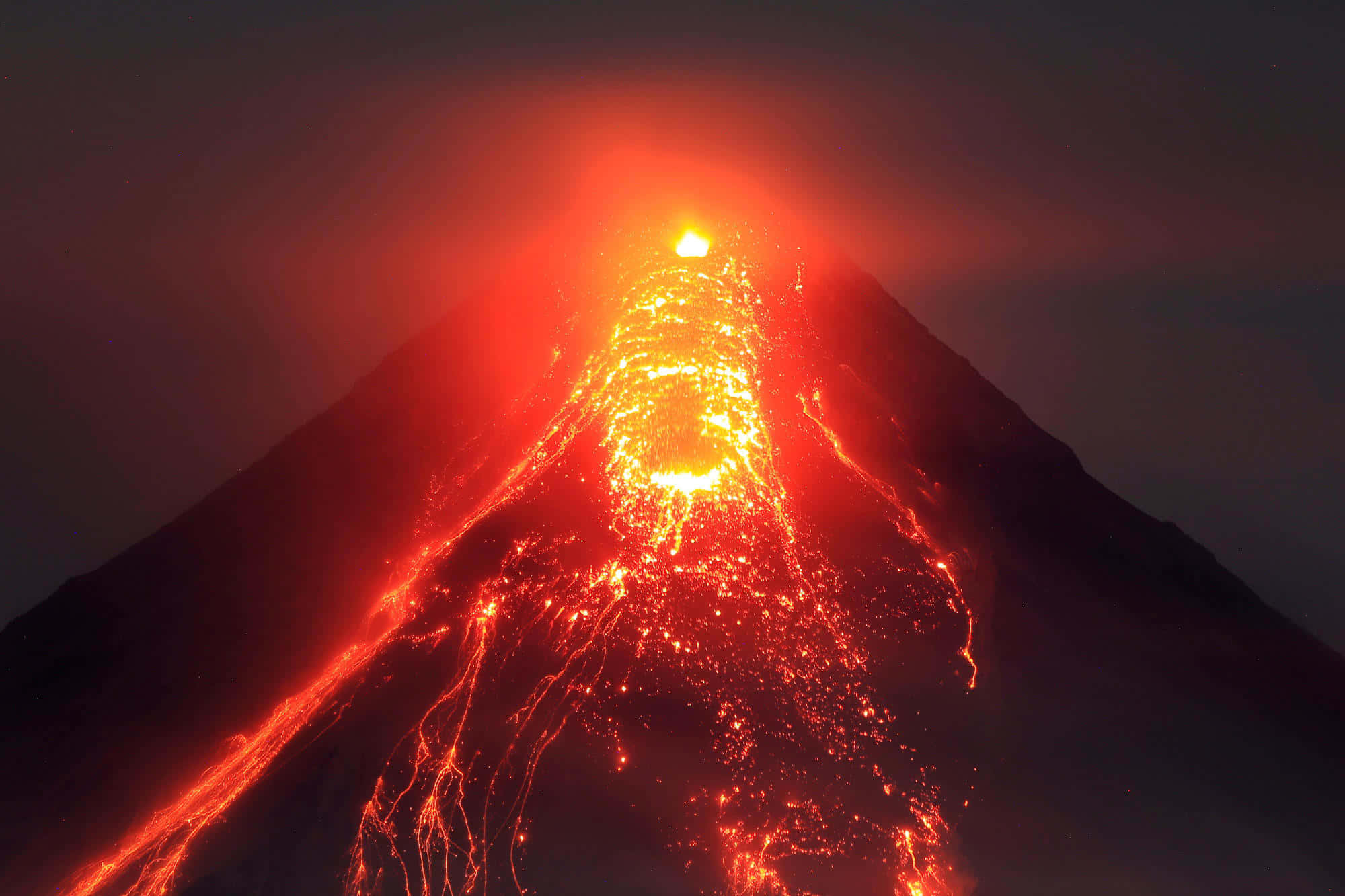 View of an erupting volcano at the night sky