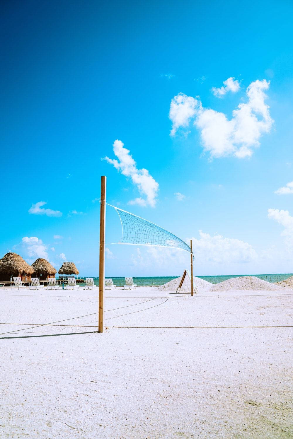 a beach with a volleyball net and chairs Wallpaper