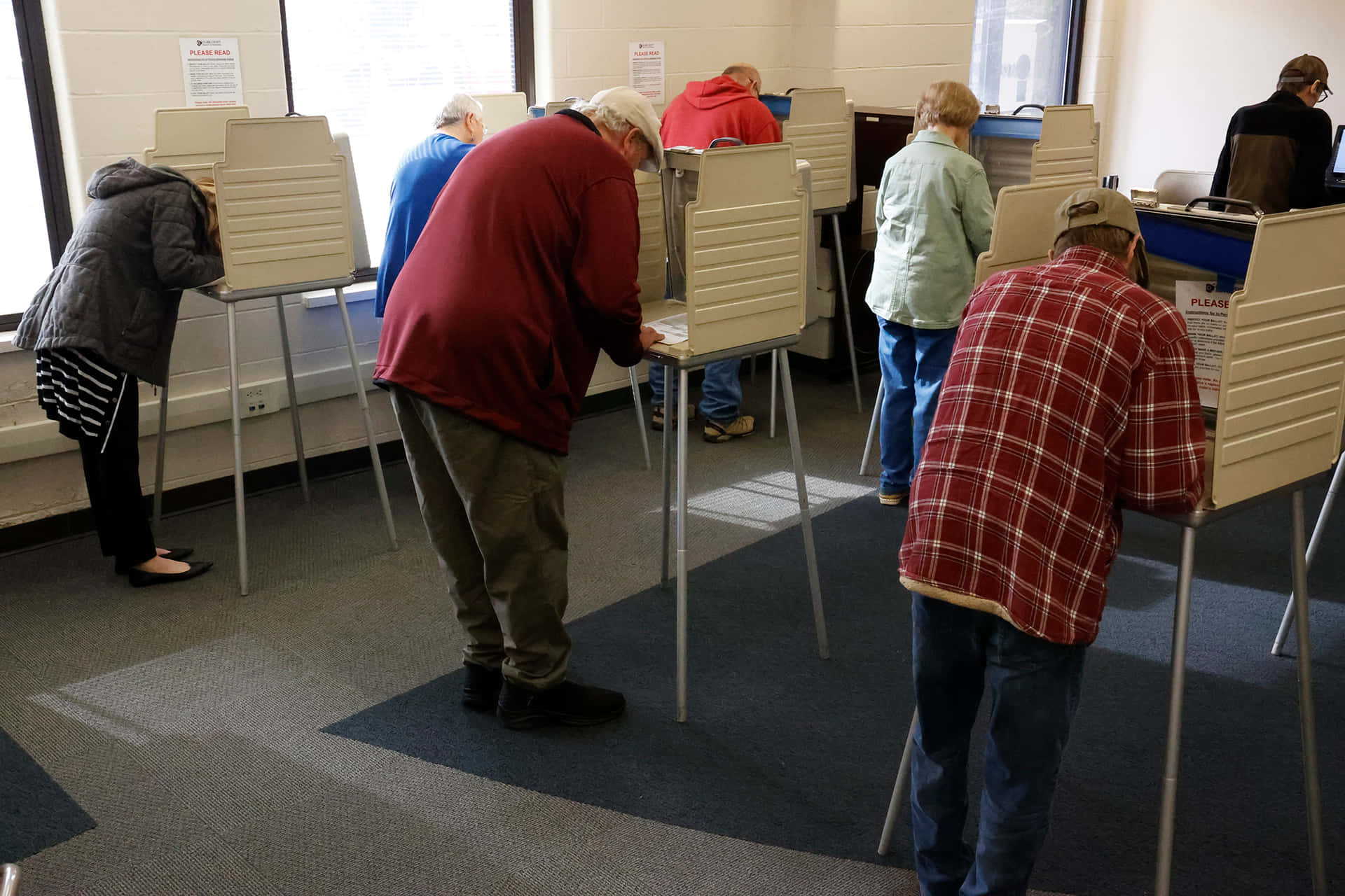 Personasvotando En Una Sala Con Cabinas De Votación