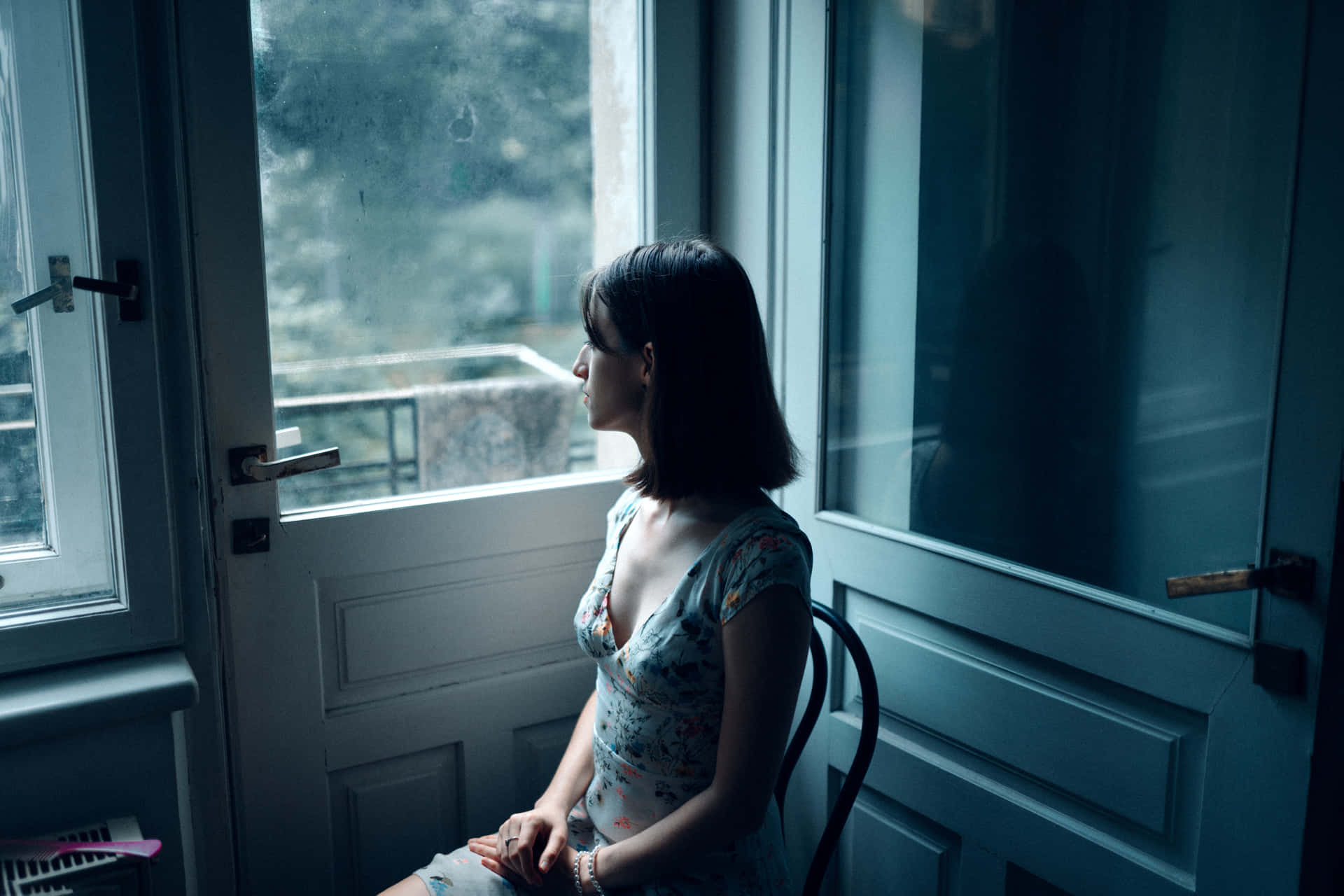 A Woman Sitting In A Chair Looking Out A Window