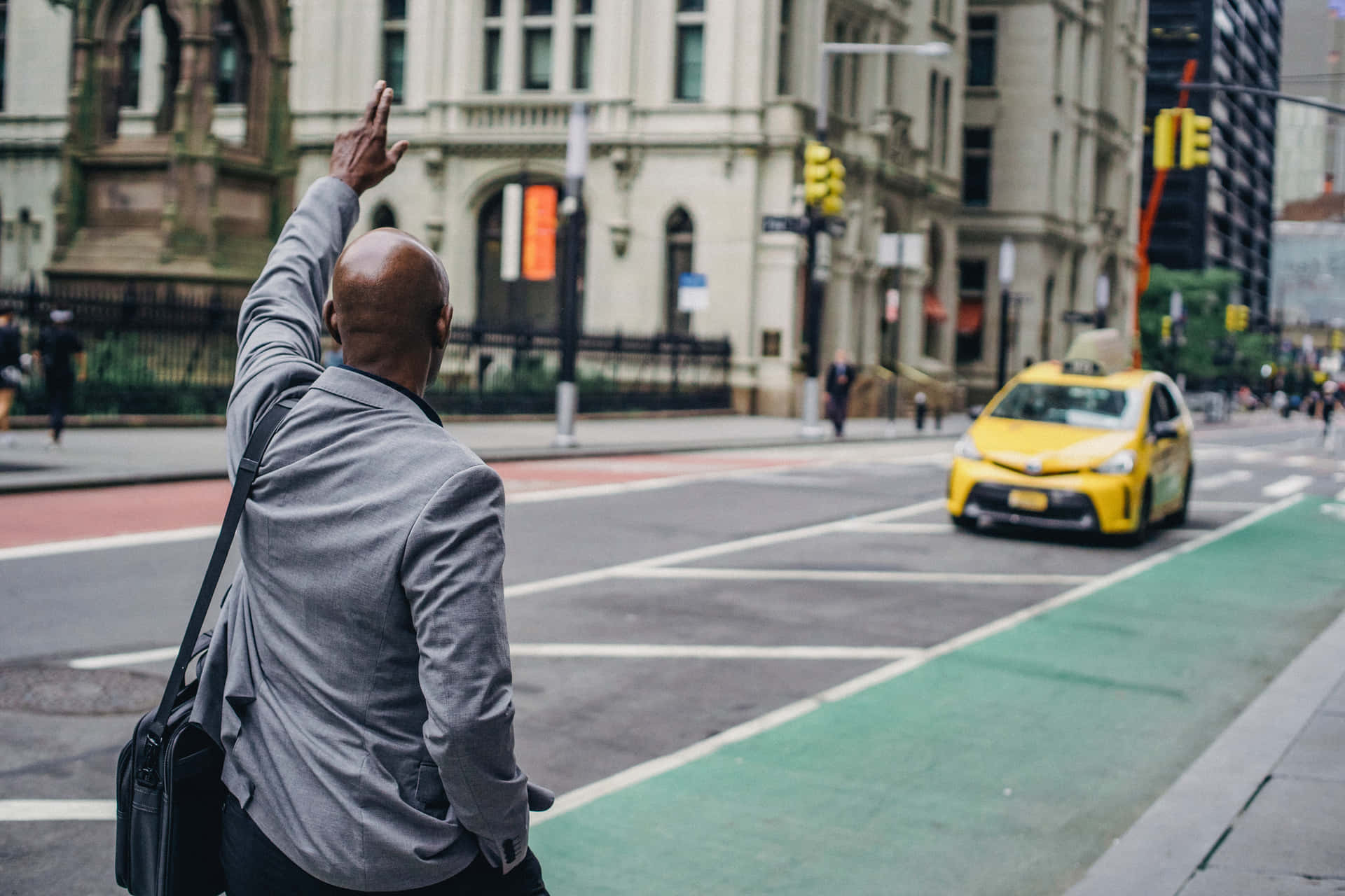 A Man Waving At A Taxi On The Street