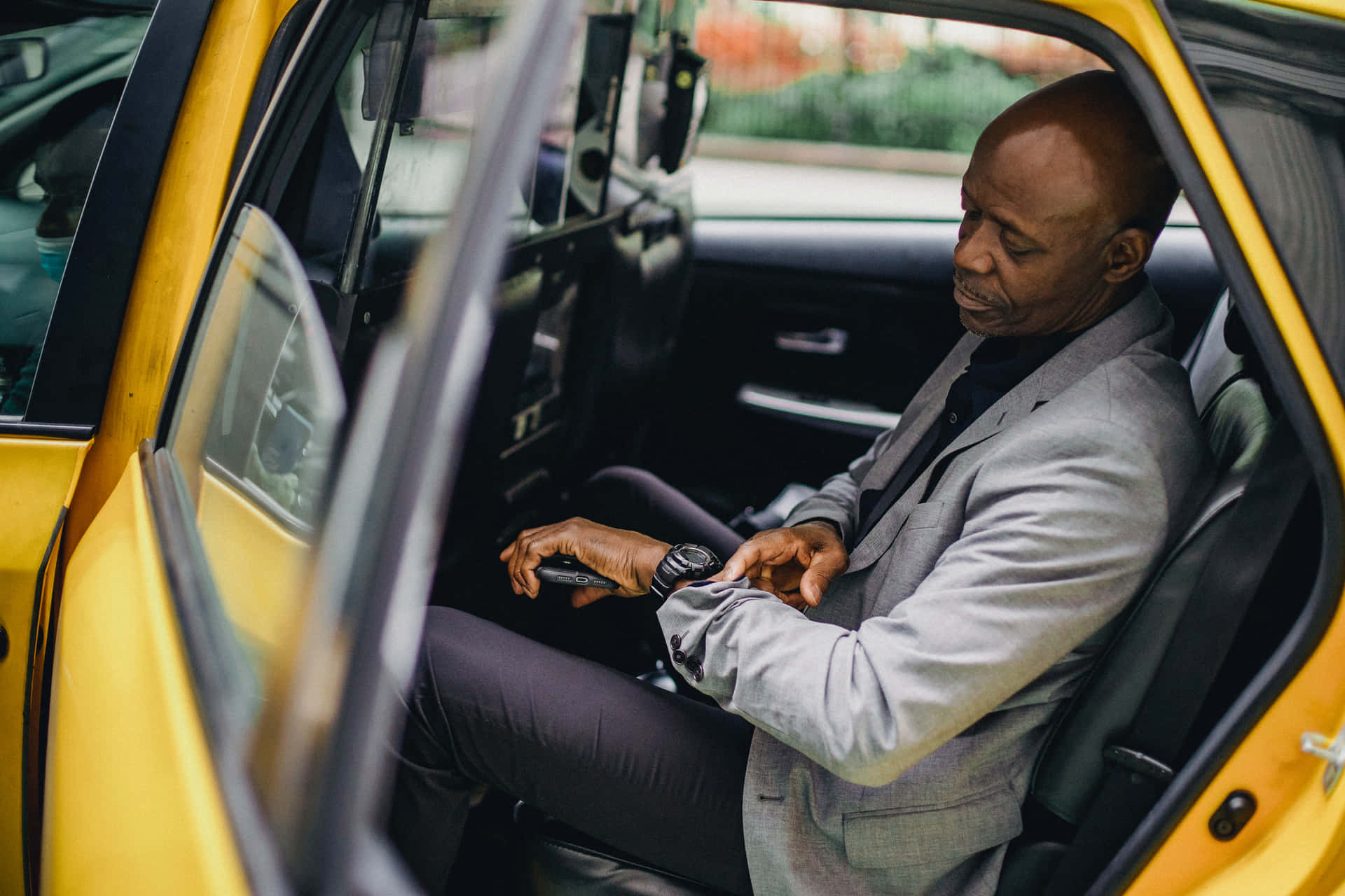 A Man Sitting In The Back Seat Of A Yellow Taxi