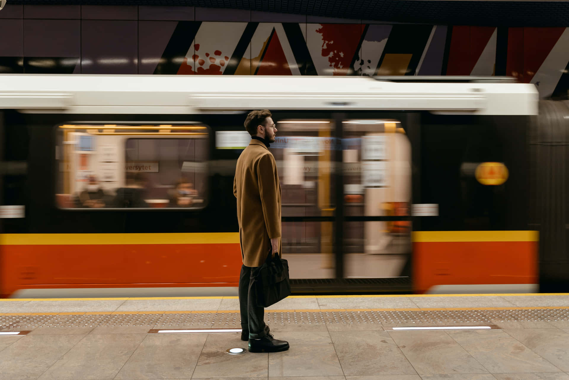A Man Standing On A Platform Waiting For A Train
