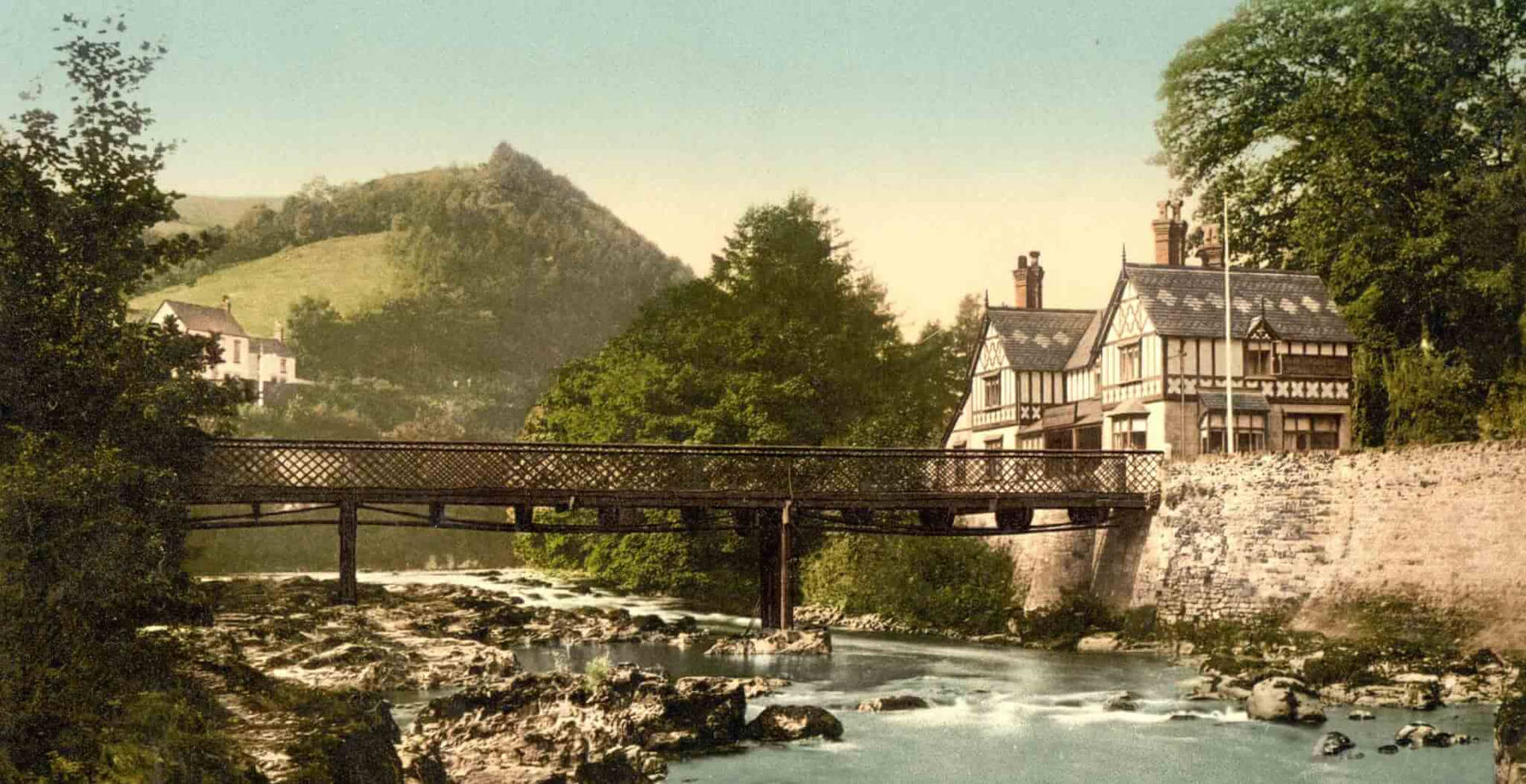 A Bridge Over A River With Houses In The Background Wallpaper