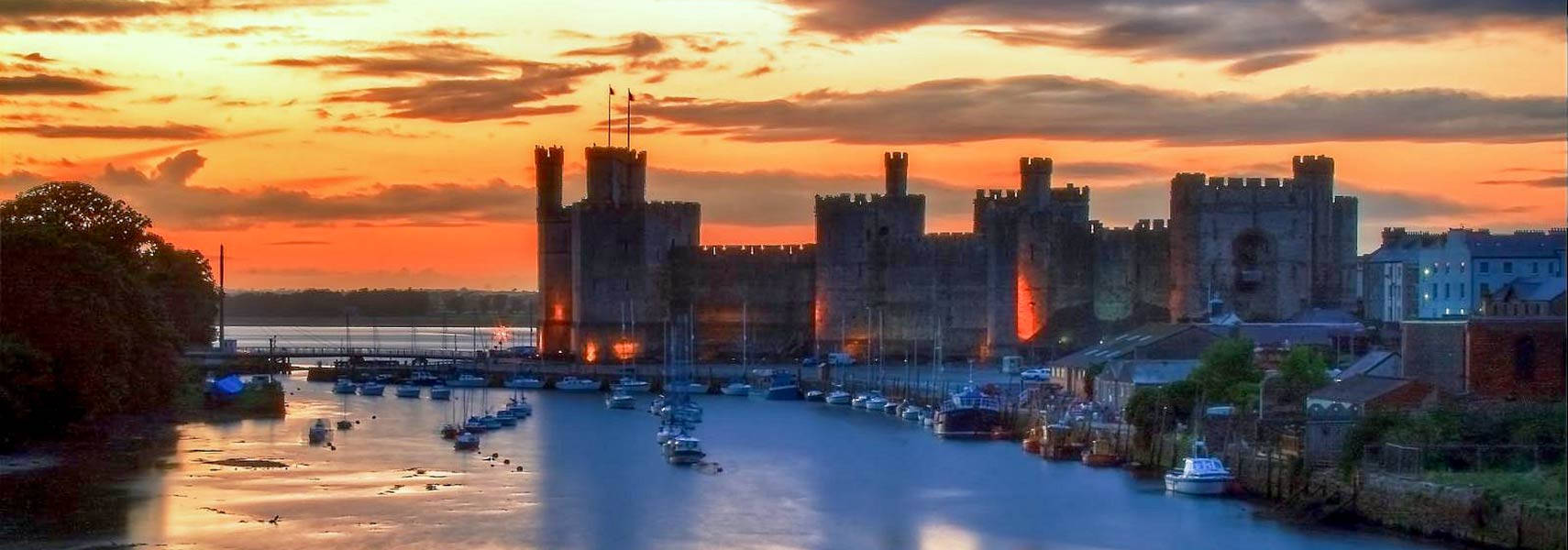 a castle with boats on the water at sunset Wallpaper