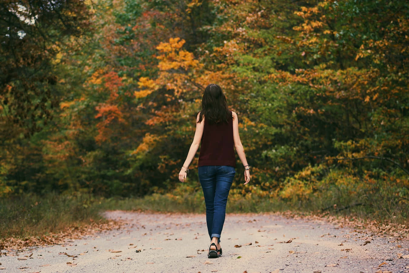 A Woman Walking Down A Path In The Woods
