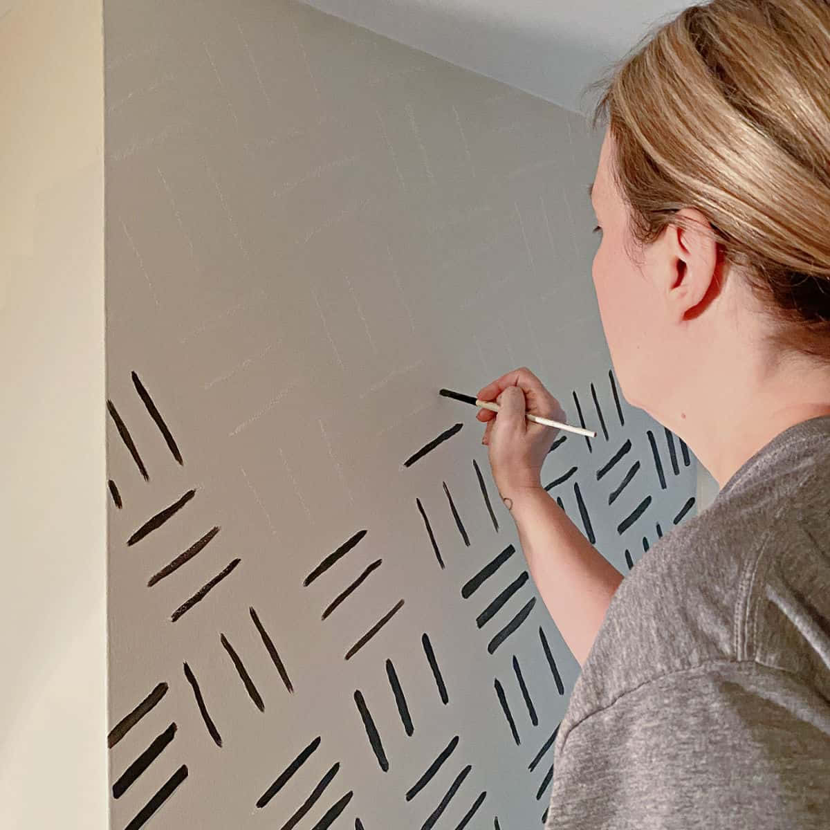 A Woman Painting A Wall With Black And White Stripes