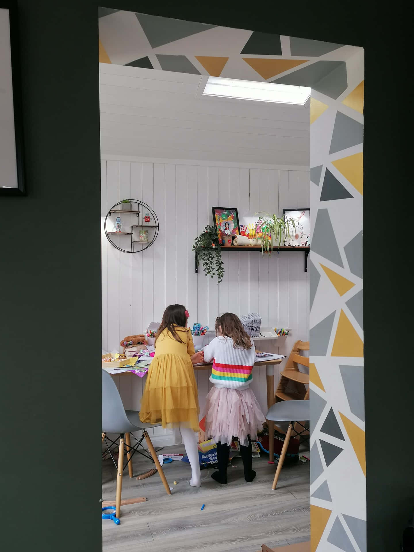 Two Children Are Sitting In A Room With Geometric Patterns