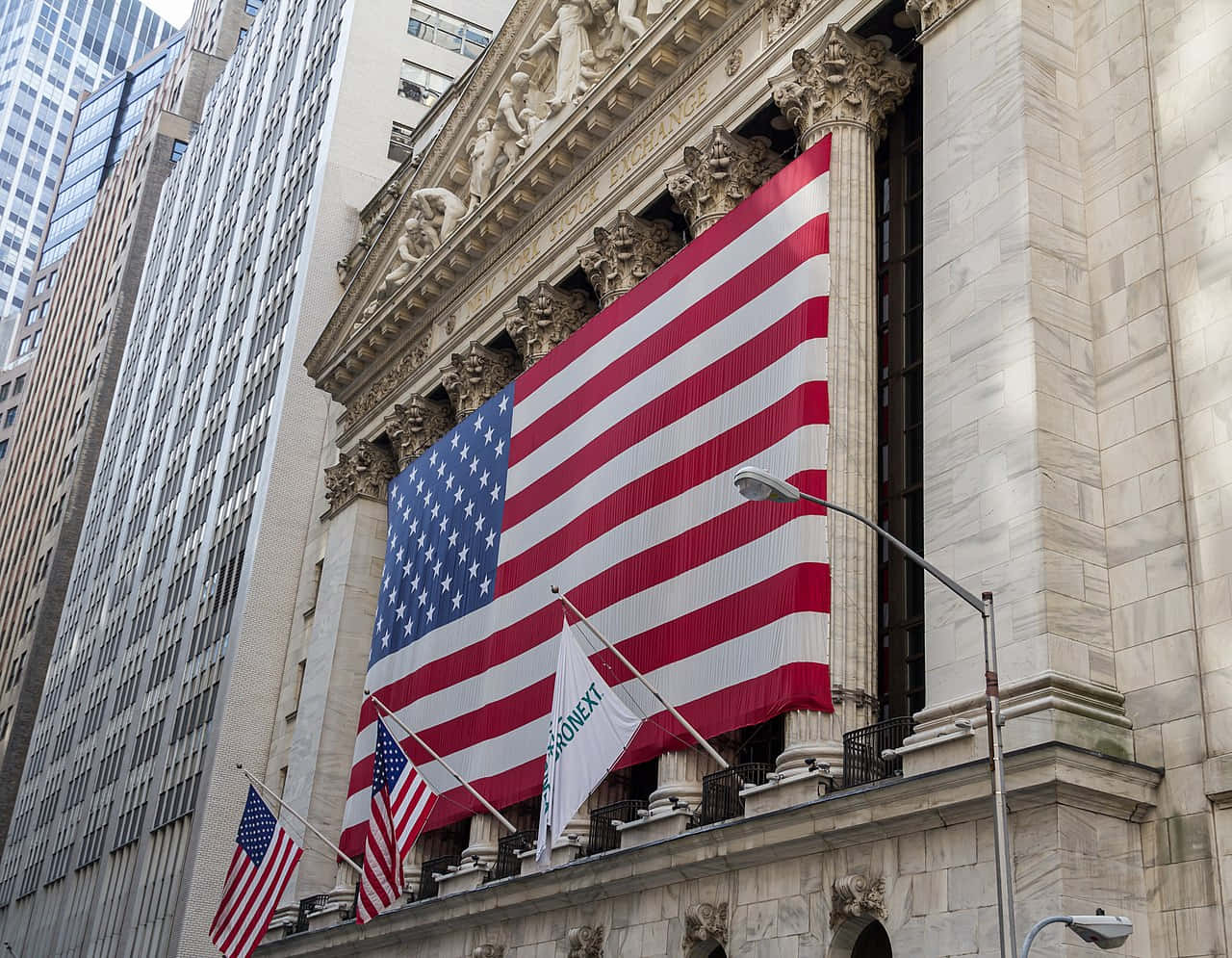Unagran Bandera Estadounidense Está En La Pared De La Bolsa De Valores De Nueva York. Fondo de pantalla